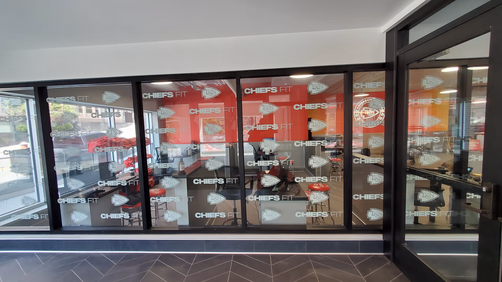 Glass-walled lobby with Chiefs Fit branding and seating inside a modern interior.