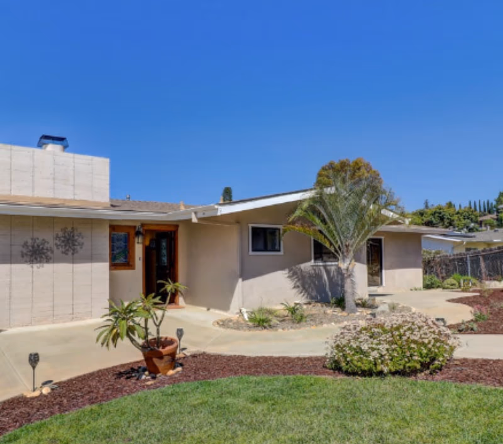 Single-story senior living facility exterior with palm tree and landscaped front yard.
