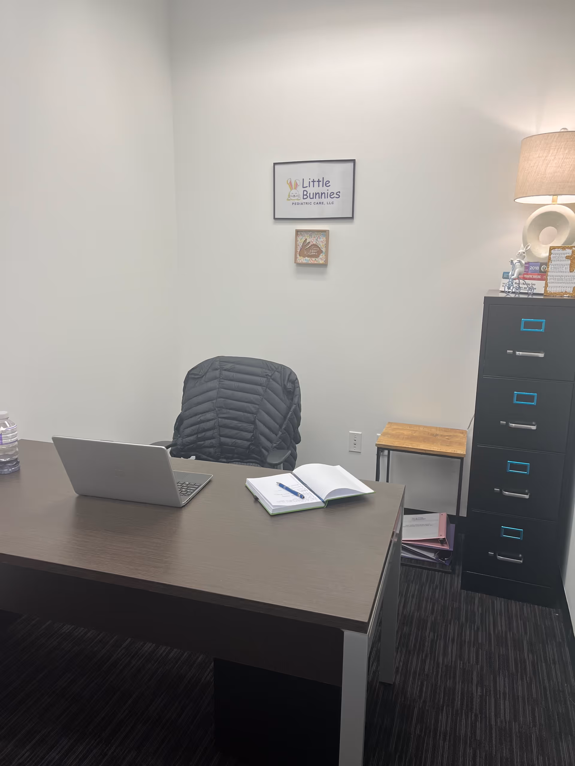 Office desk setup with laptop, notebook, chair, and filing cabinet