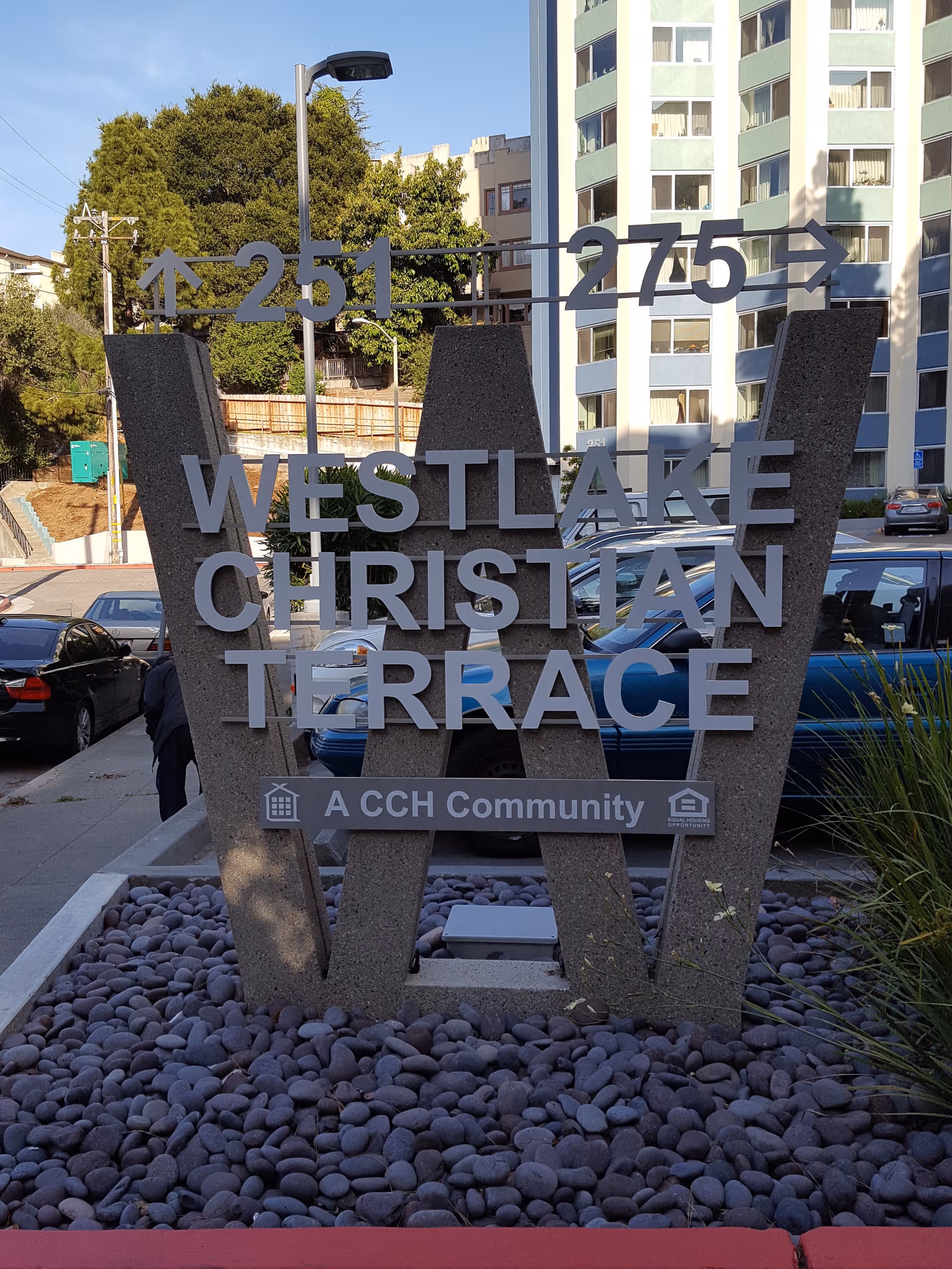 Westlake Christian Terrace entrance sign with a tall building behind and parked cars.
