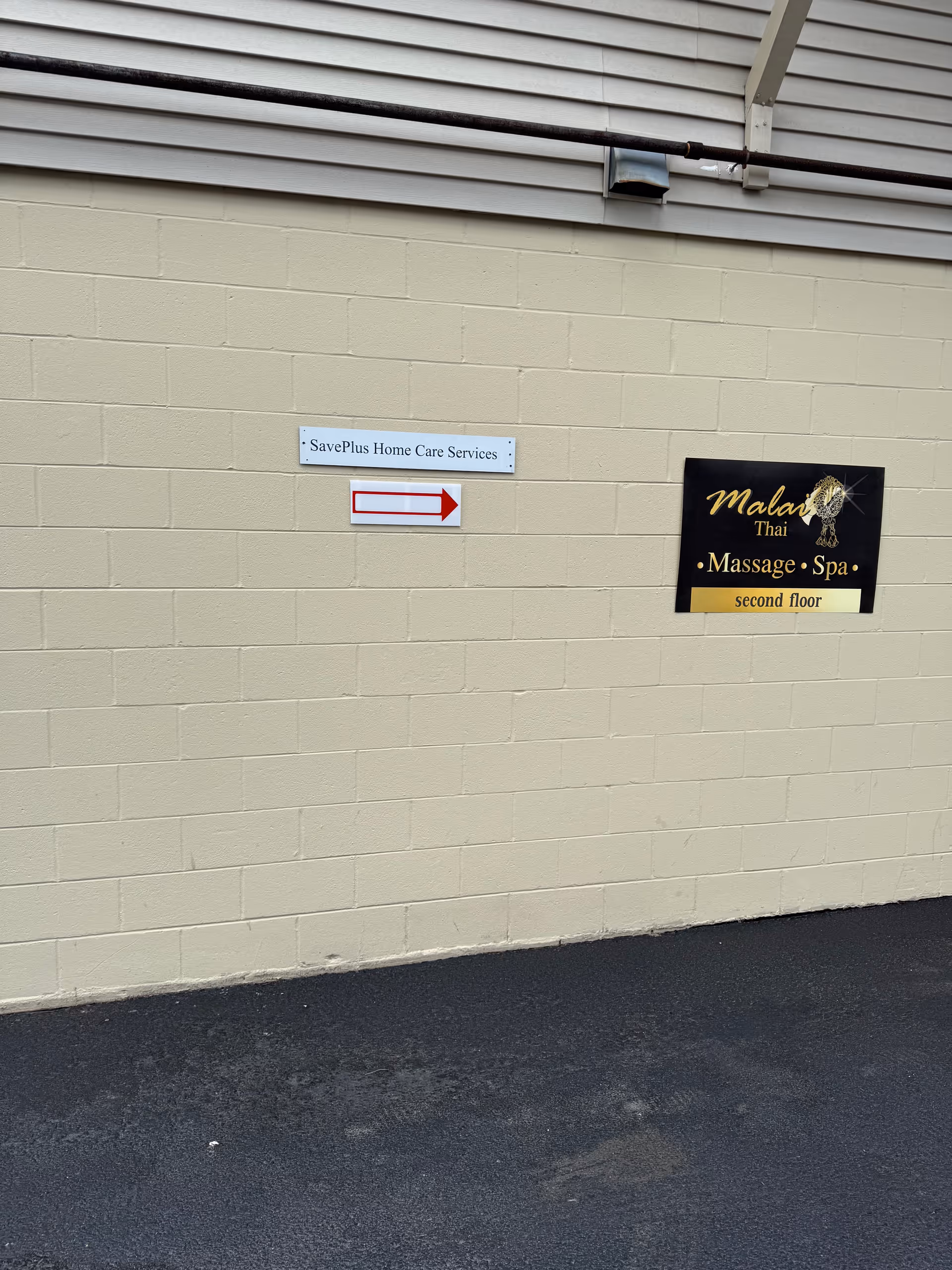 Exterior beige wall with SavePlus Home Care Services and a Thai massage spa sign.