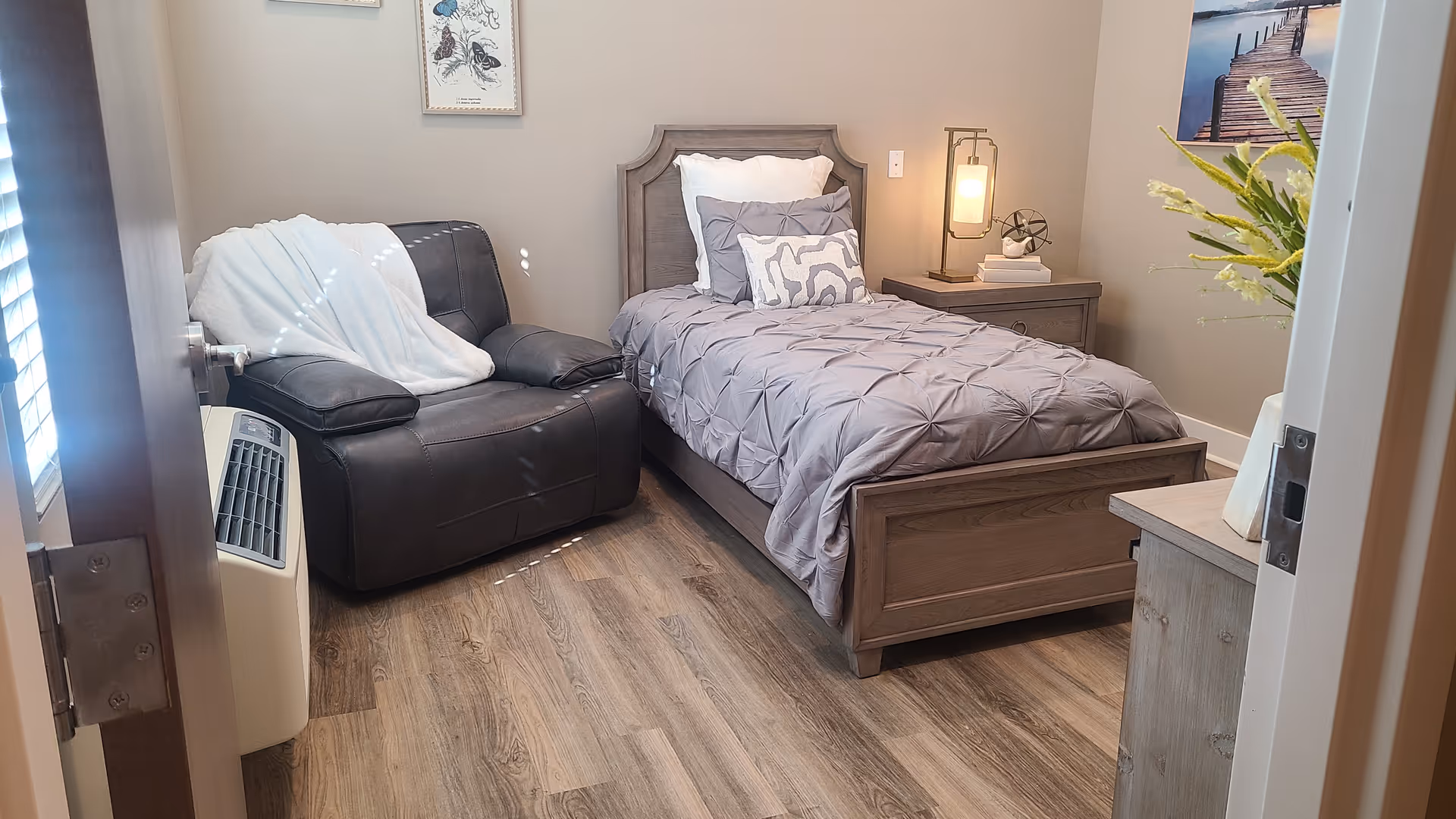 Cozy bedroom featuring a bed, leather recliner, nightstand, and decorative wall art.