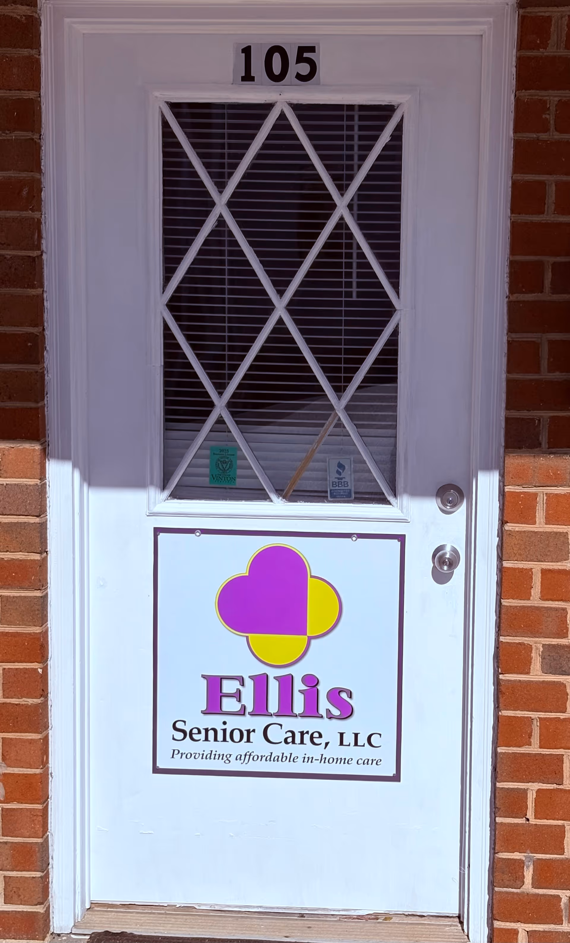 White front door with diamond grille, brick exterior, 105, Ellis Senior Care sign.