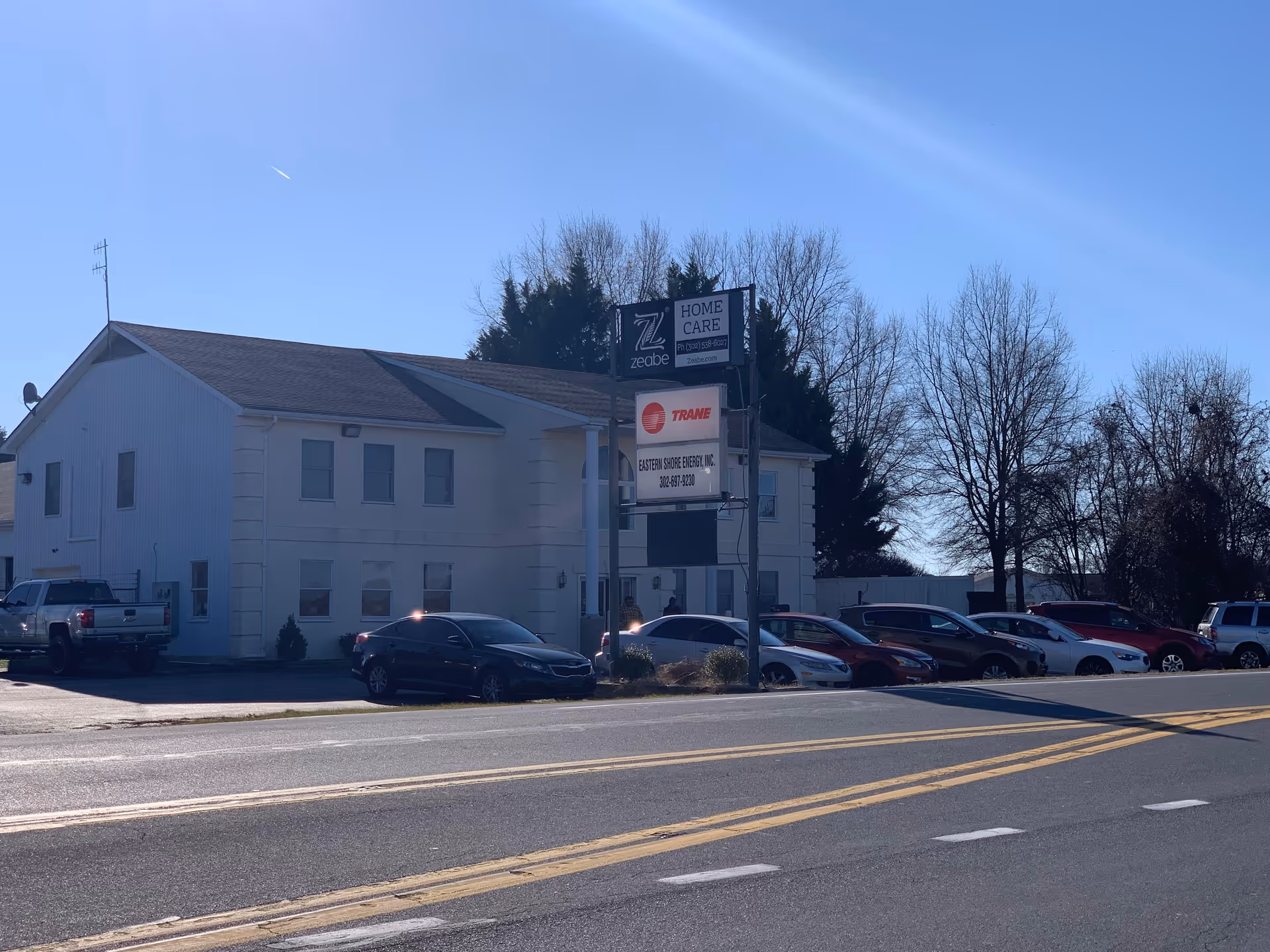 White two-story building with Zeabe Home Care sign and parked cars.