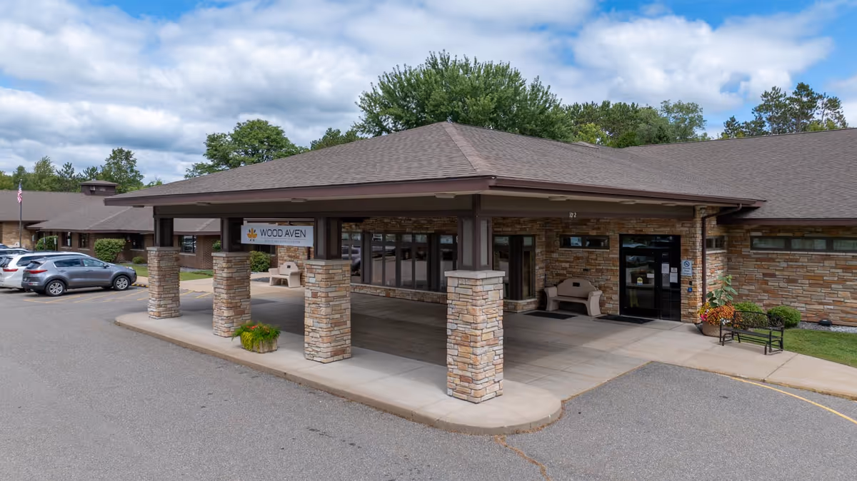 Exterior view of Benedictine Living Community-Wausau entrance with a covered porte-cochere and stone columns.