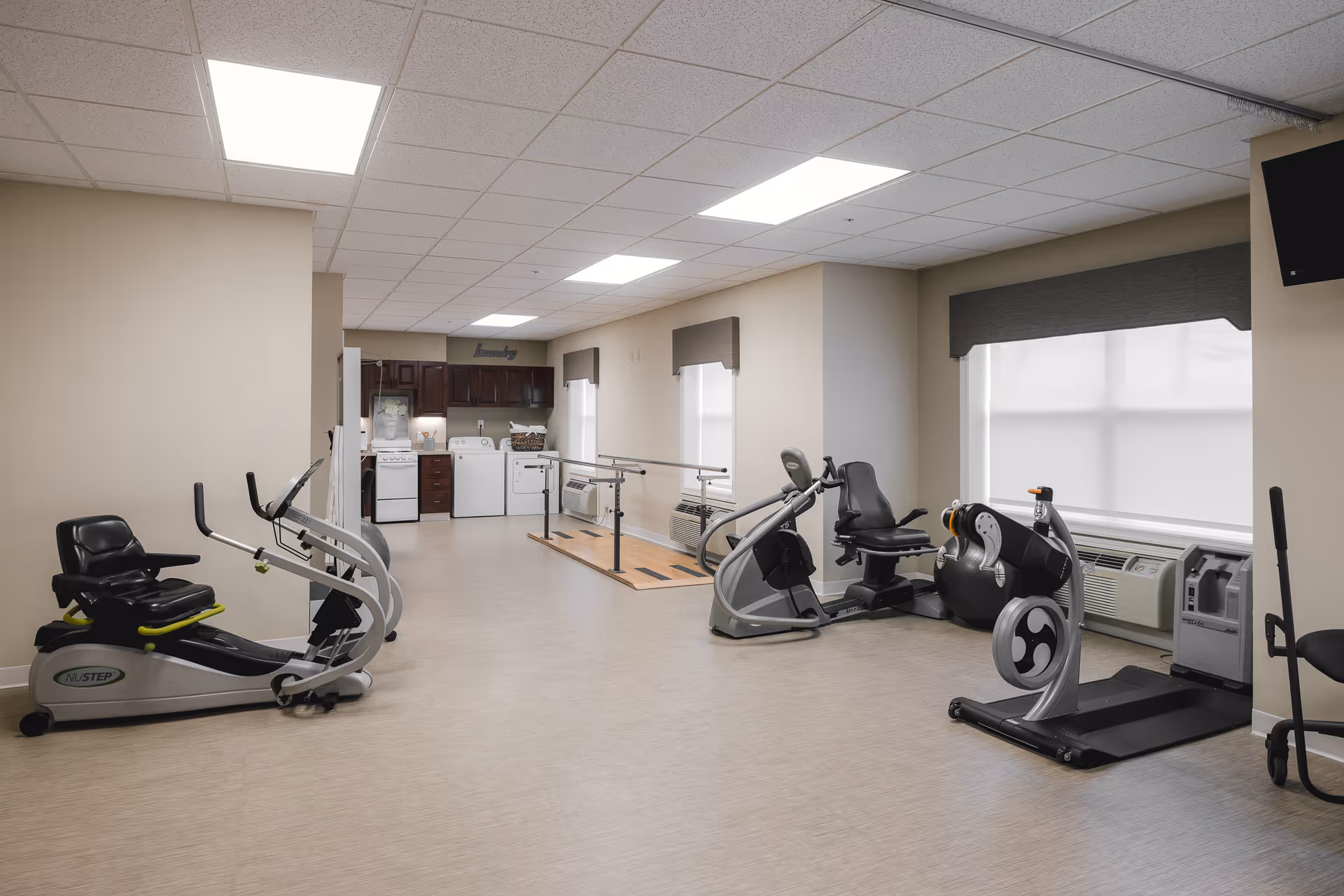 Interior gym area with cardio machines and open space in a senior living facility.