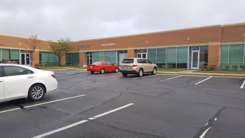 Front view of All American Home Healthcare facility with a parking lot.