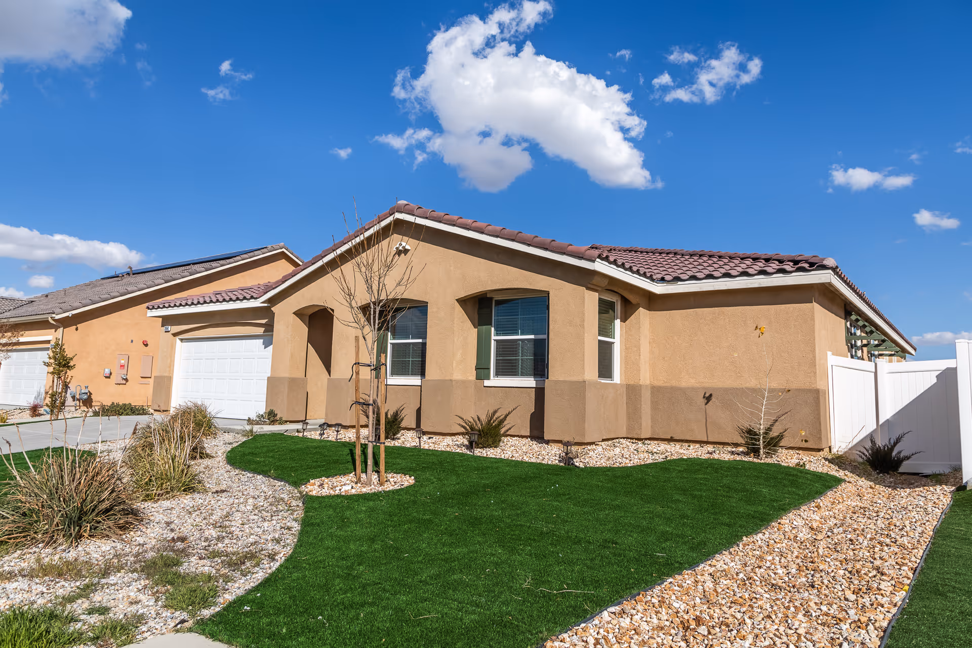Single-story tan building with a red-tiled roof, well-kept lawn, and clear blue sky.