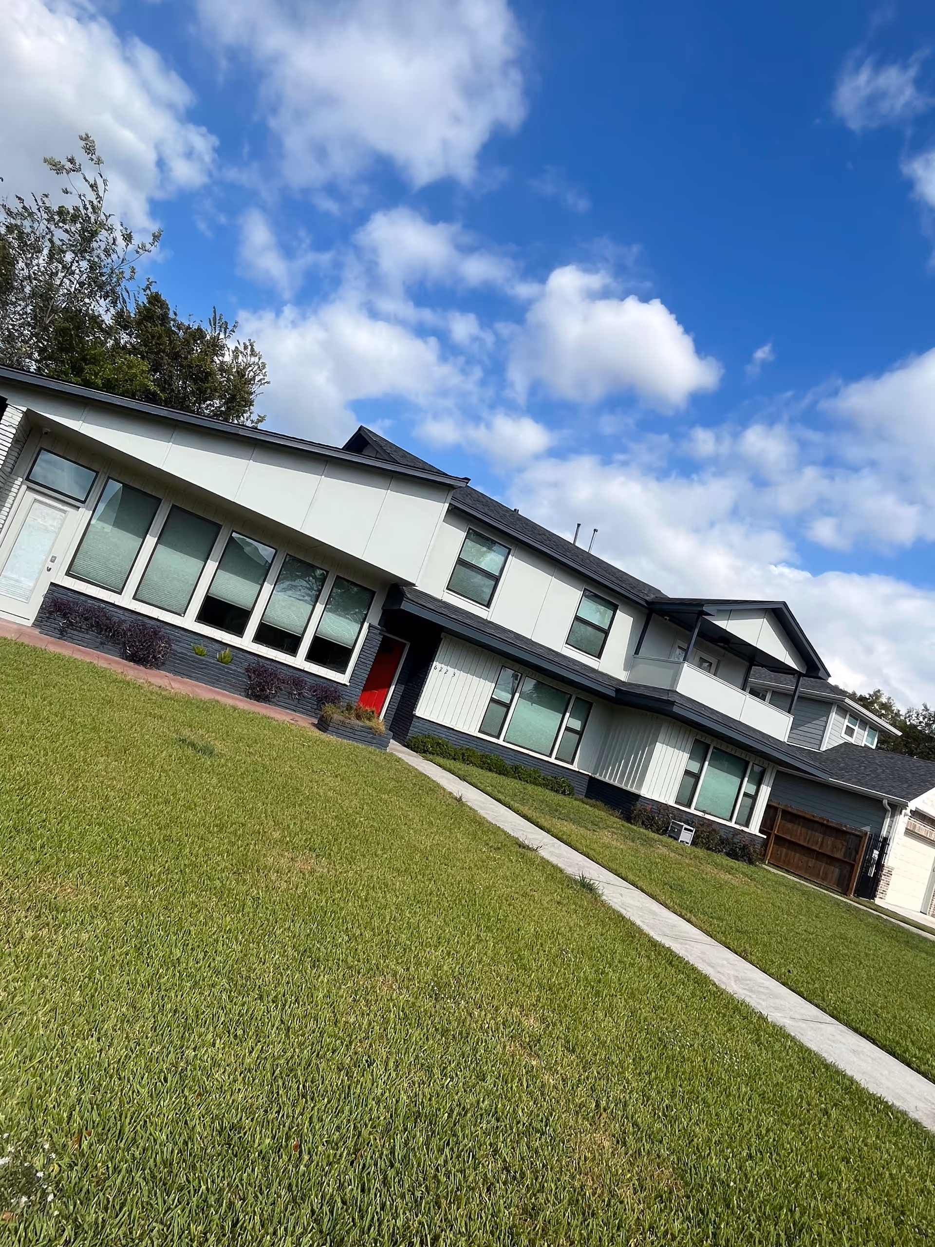 Modern two-story senior living facility front exterior with green lawn and walkway.