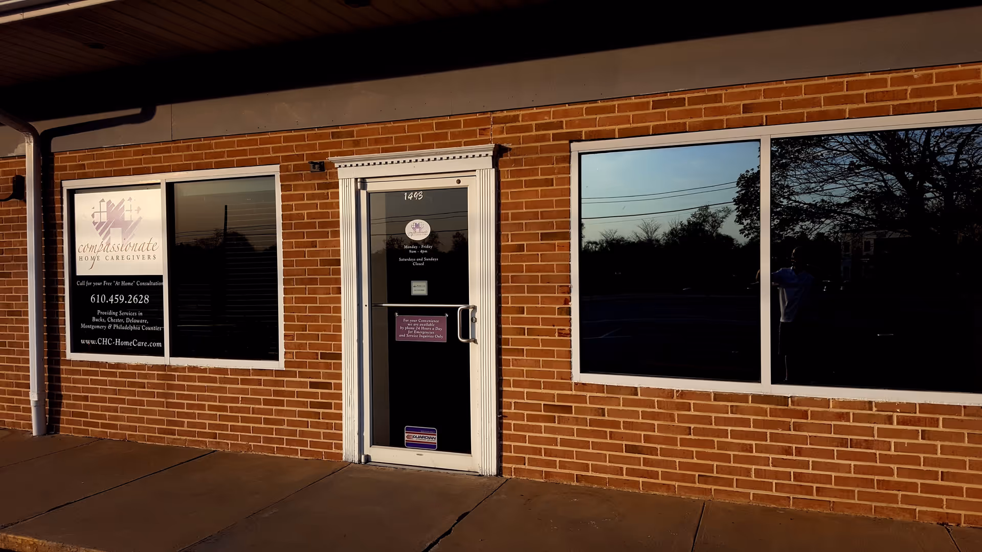 Brick building exterior with Compassionate Home Caregivers sign and glass door