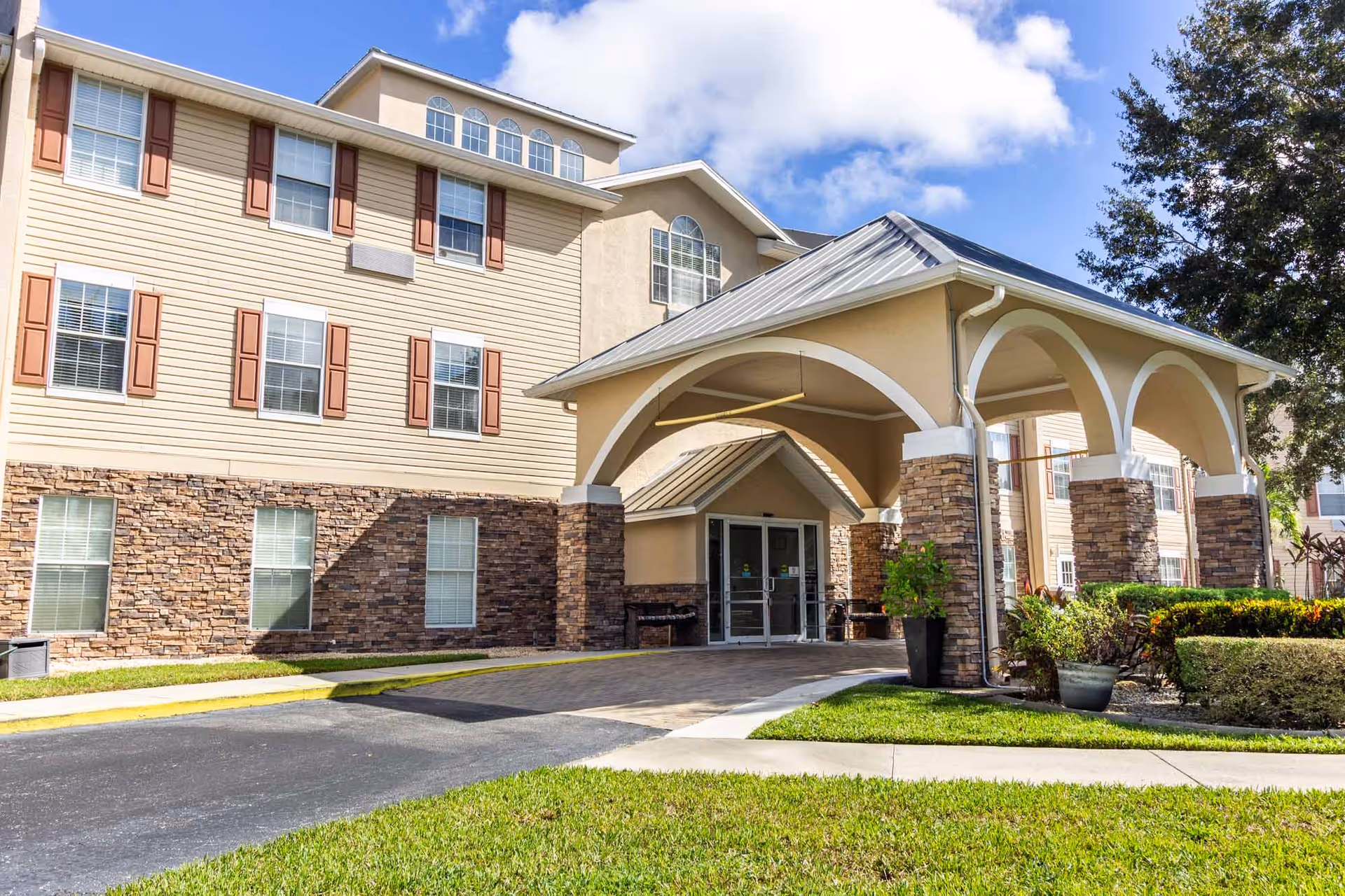 Exterior view of Fountain Crest Retirement Community with arched entrance and stone facade.