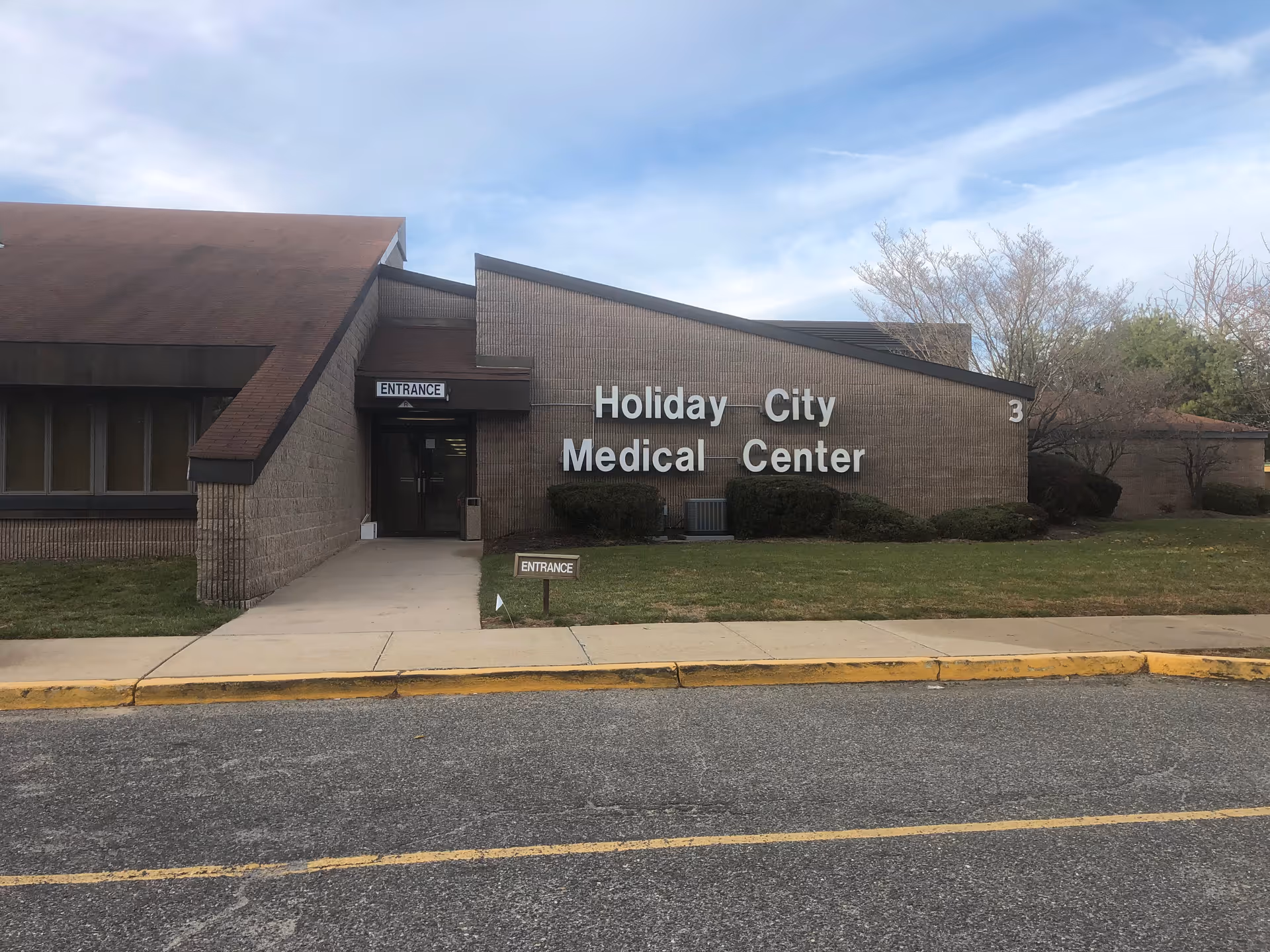 Brick medical center exterior with a large white sign reading Holiday City Medical Center.