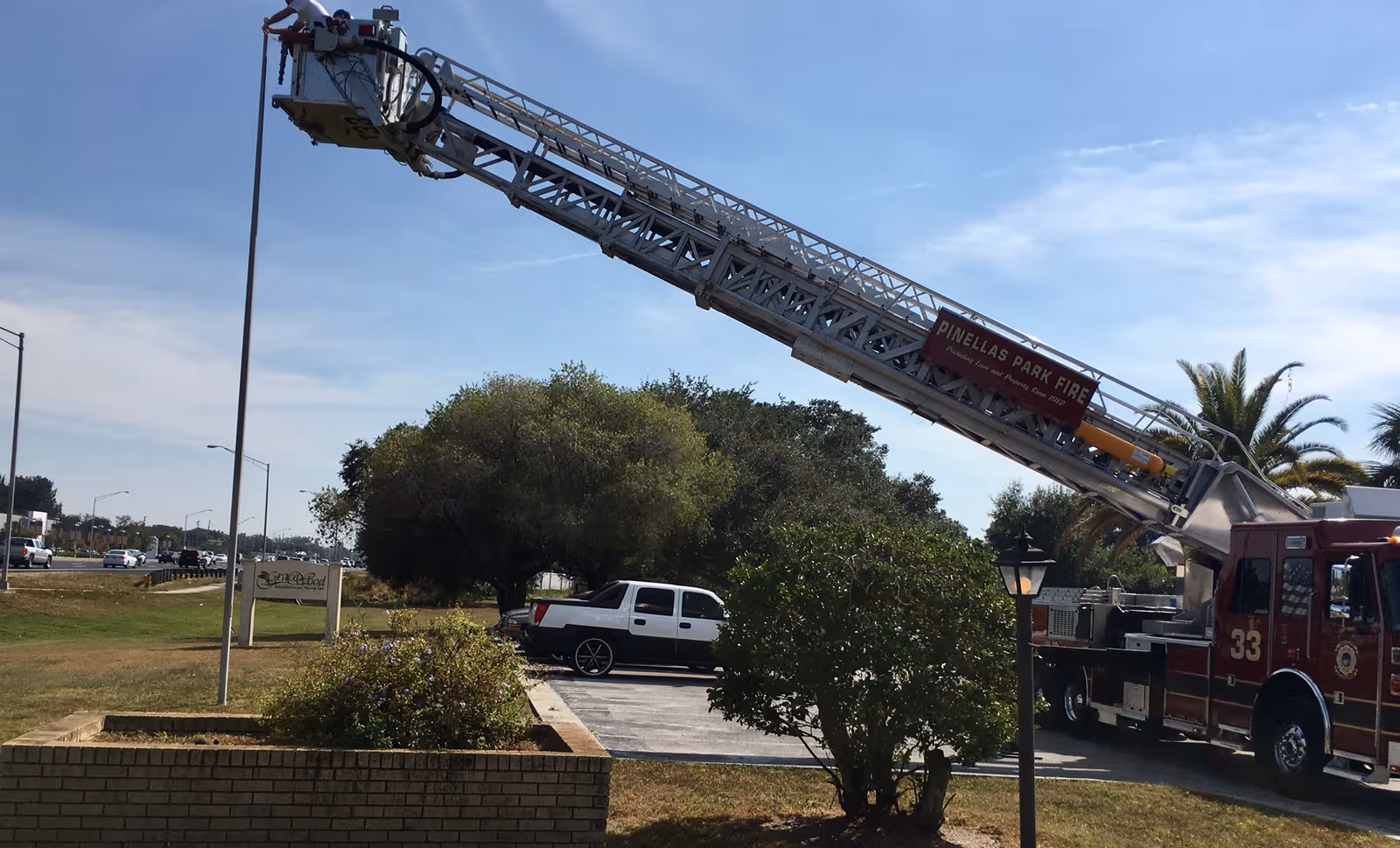 Fire truck with extended ladder parked in a lot near a senior care facility.