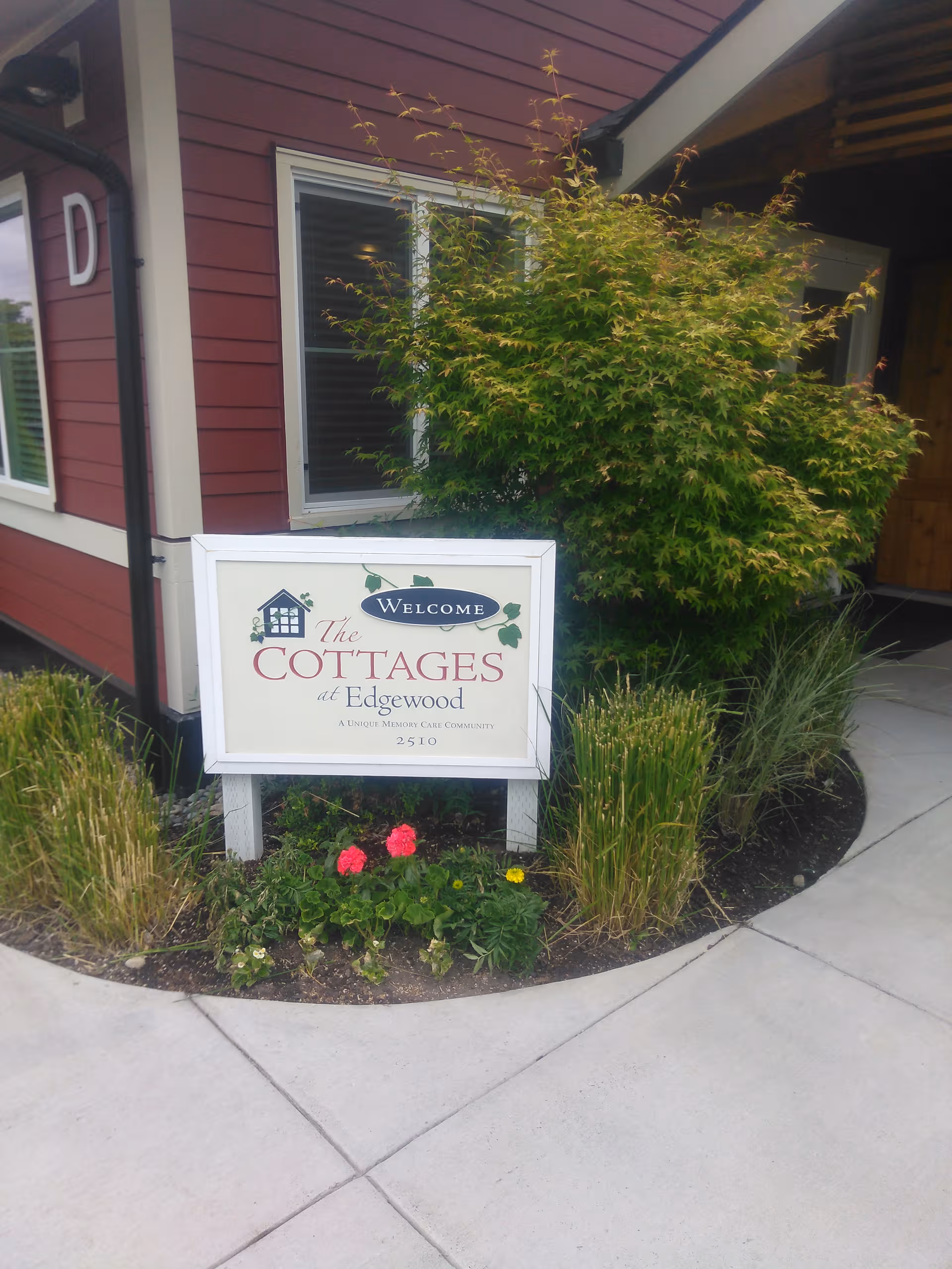 Front of a red building with a welcome sign and surrounding garden.