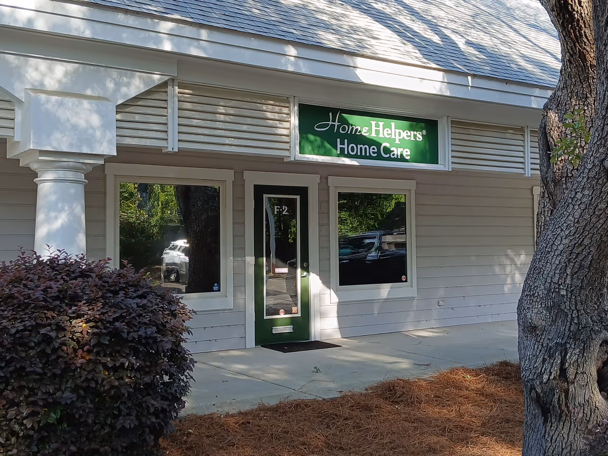 Front of a light-gray building with a green Home Helpers sign above the door