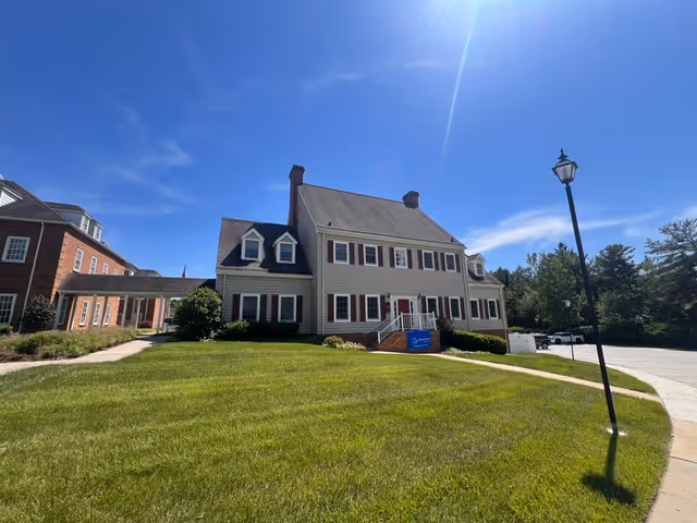 Exterior of a two-story colonial-style senior living building with a green lawn.