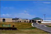 Single-story senior living facility with curved driveway, green awning, and manicured lawn