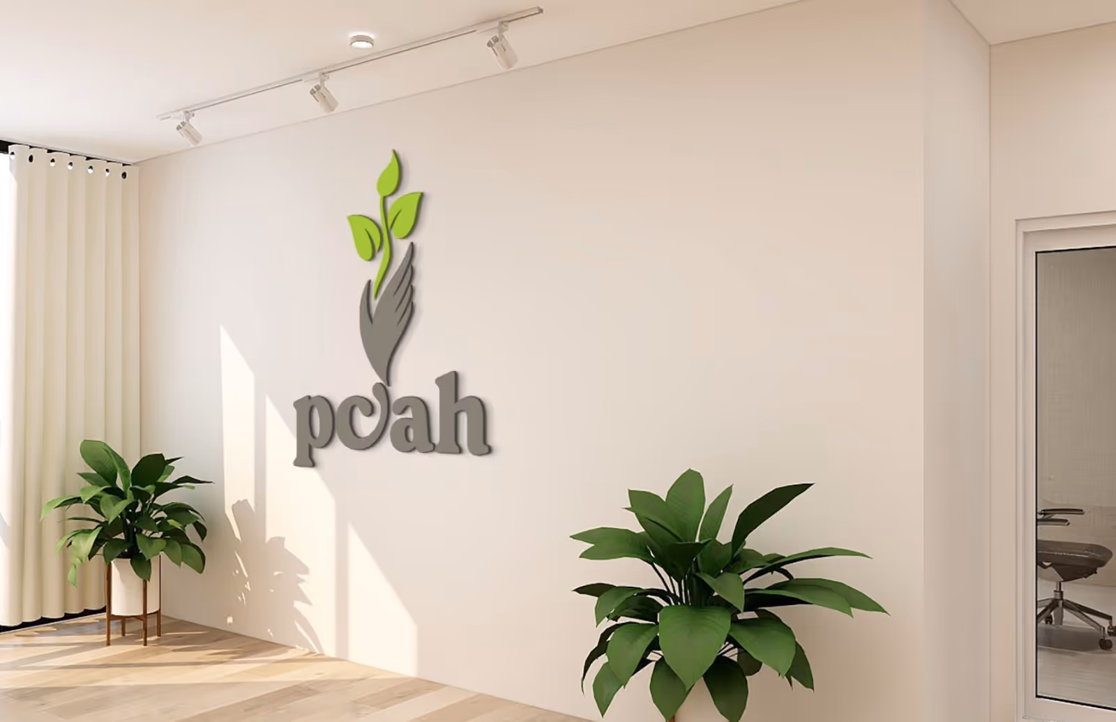 Bright interior lobby with a wall logo 'pcah', tall green plants, and a glass door.