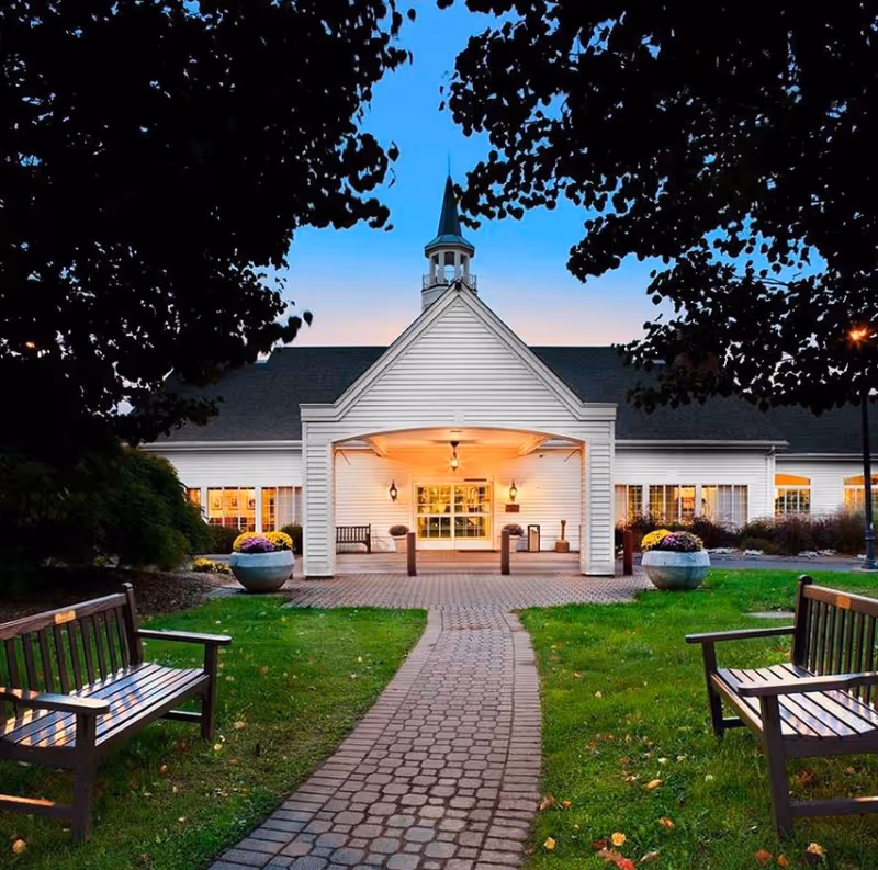 Avery Heights senior living facility entrance with brick walkway, planters, and benches.