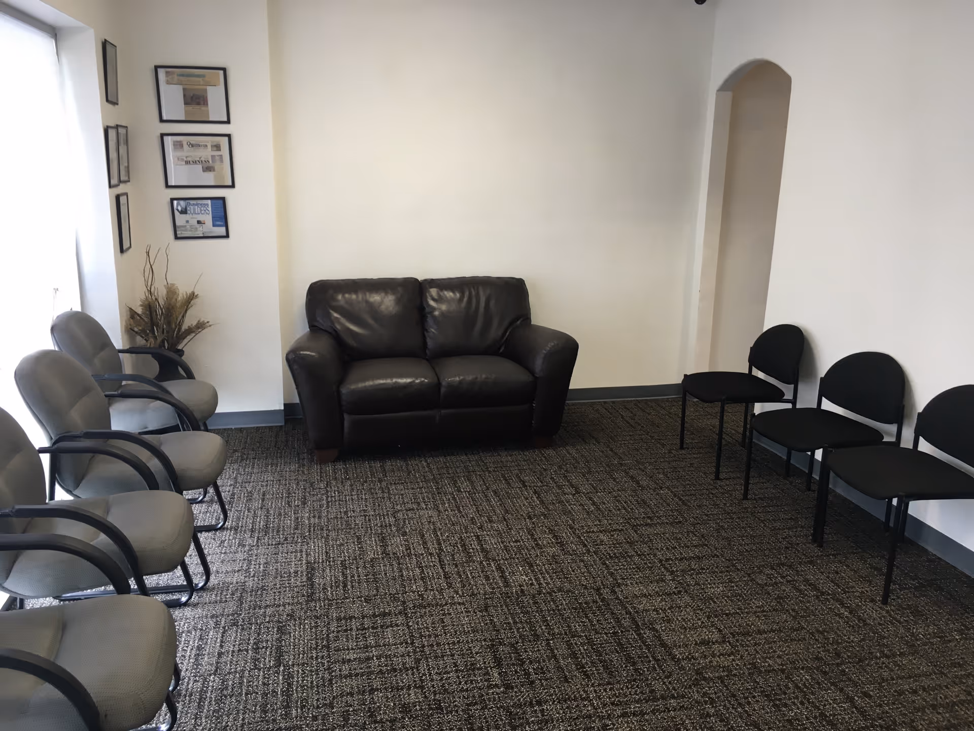 Waiting area in a senior facility with gray chairs and a black leather sofa.