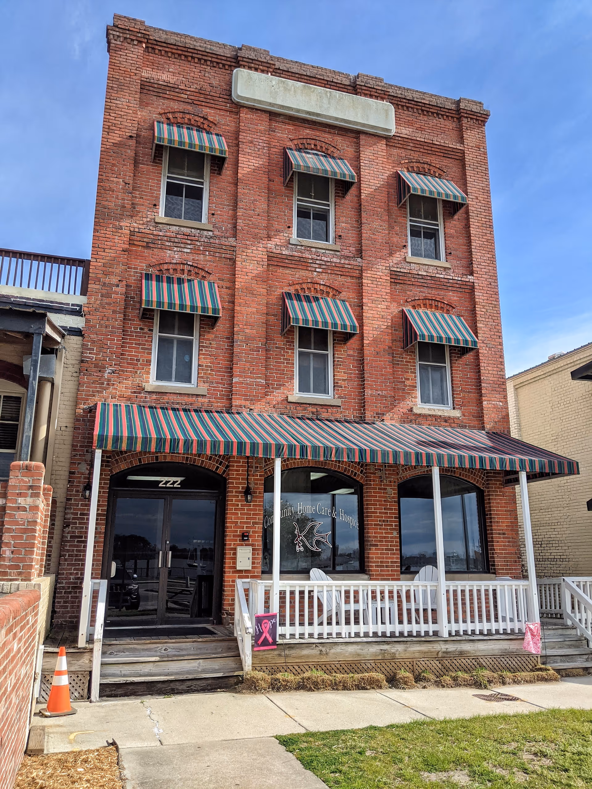 Brick building with striped awnings and a covered front porch storefront.