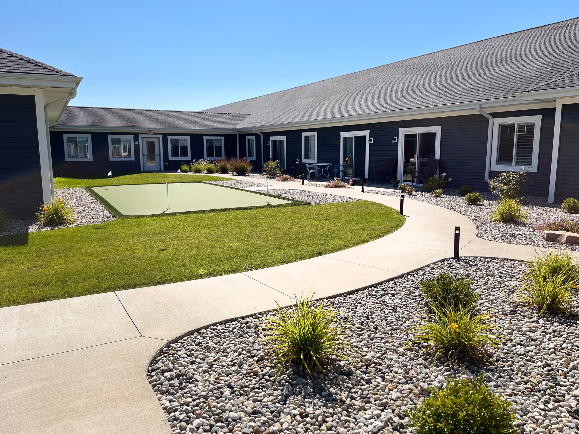 Hampton Manor of Madison exterior courtyard with curved path, gravel beds, and putting green.