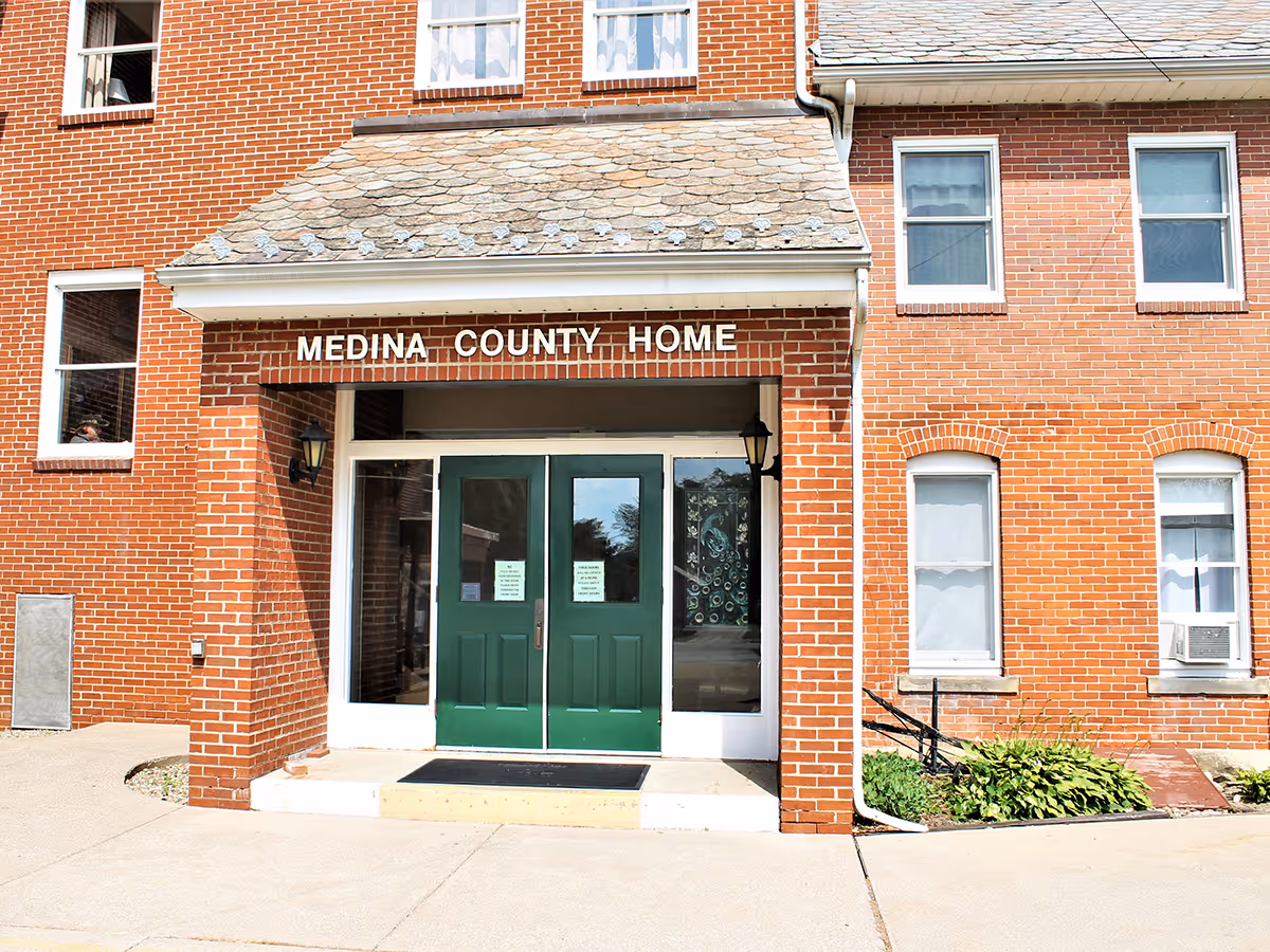 Brick Medina County Home building facade with green double doors and entry steps.