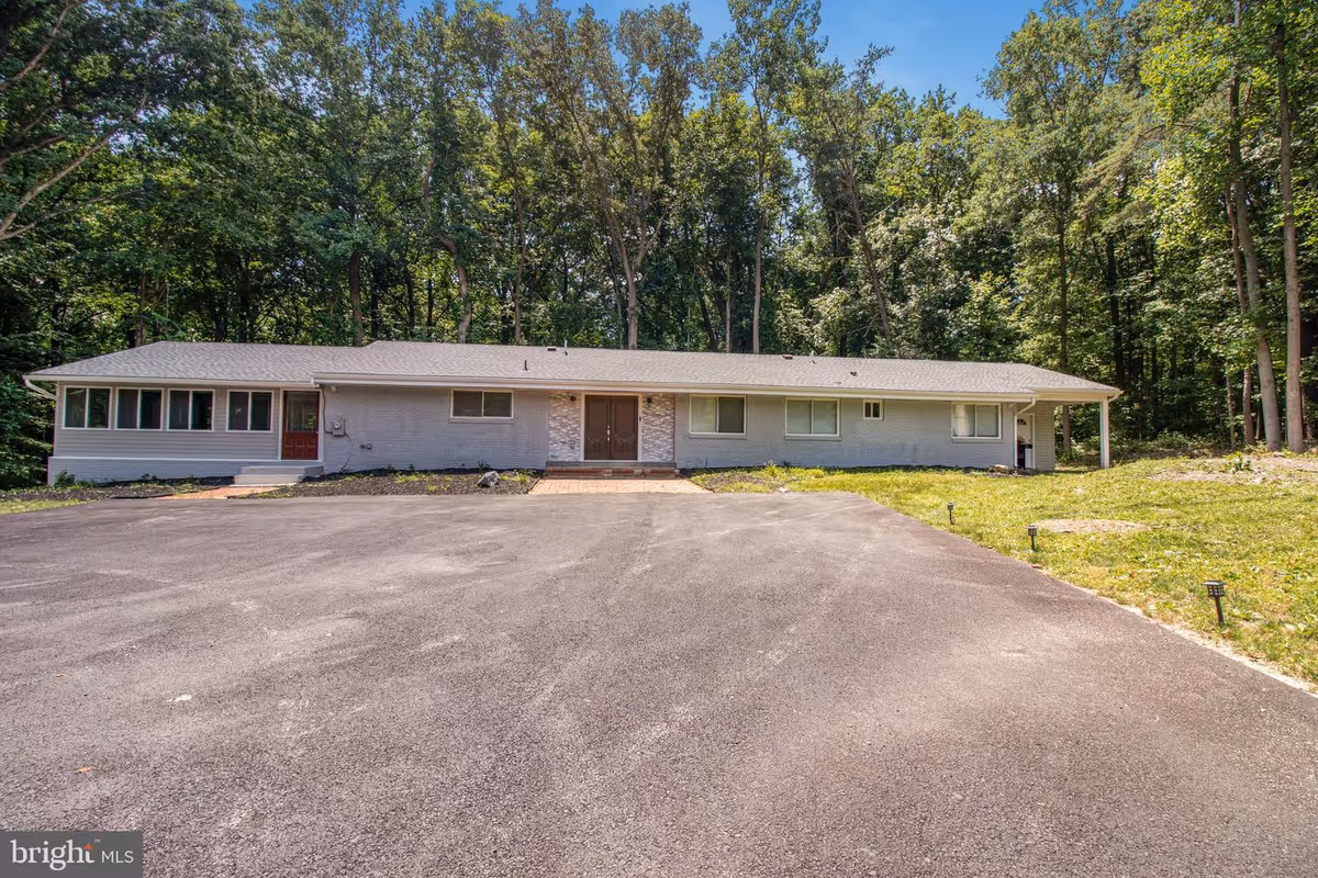 Single-story building with a long front, surrounded by trees and a paved driveway.