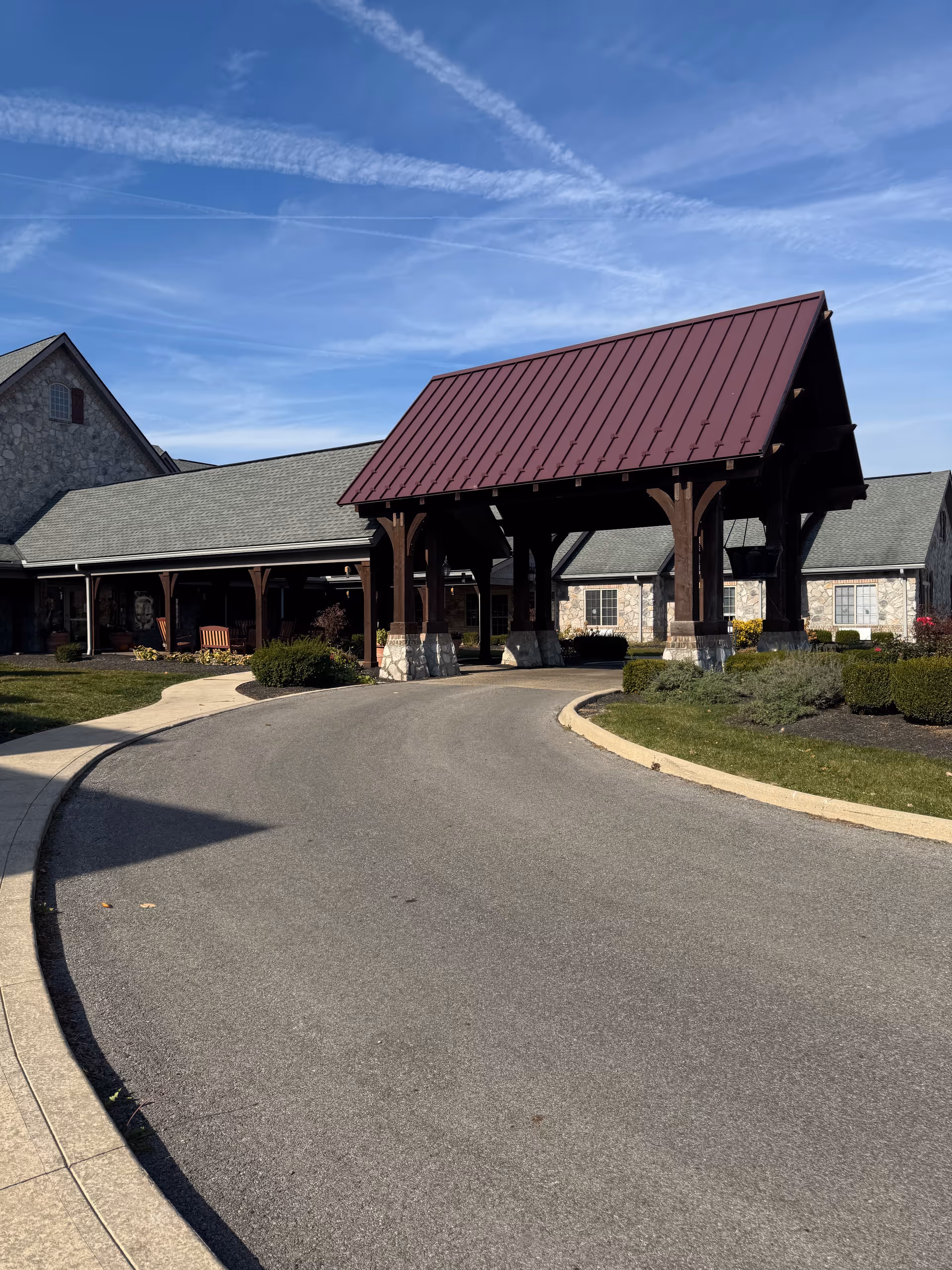 Stone building with a wooden porte-cochere entrance and curved driveway.