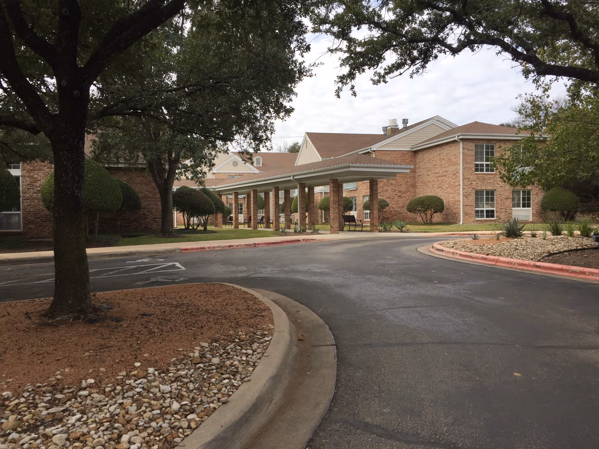 Brick senior living facility with a covered entrance and curved driveway.