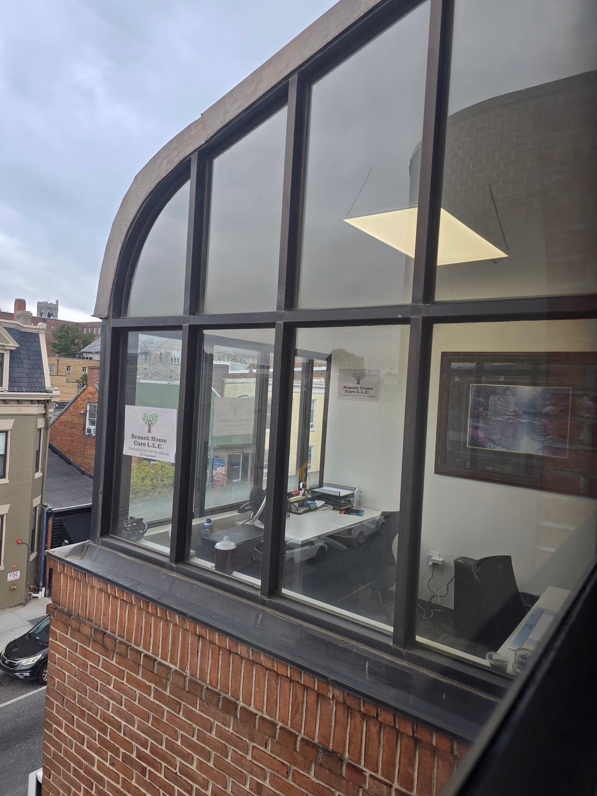 Exterior brick building with large arched windows revealing an office interior.