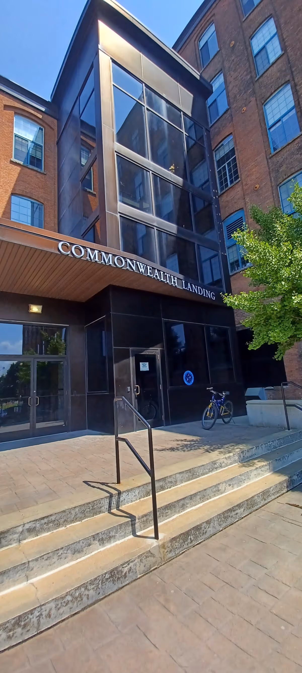 Modern brick building entrance with glass atrium and stairs, Commonwealth Landing signage.