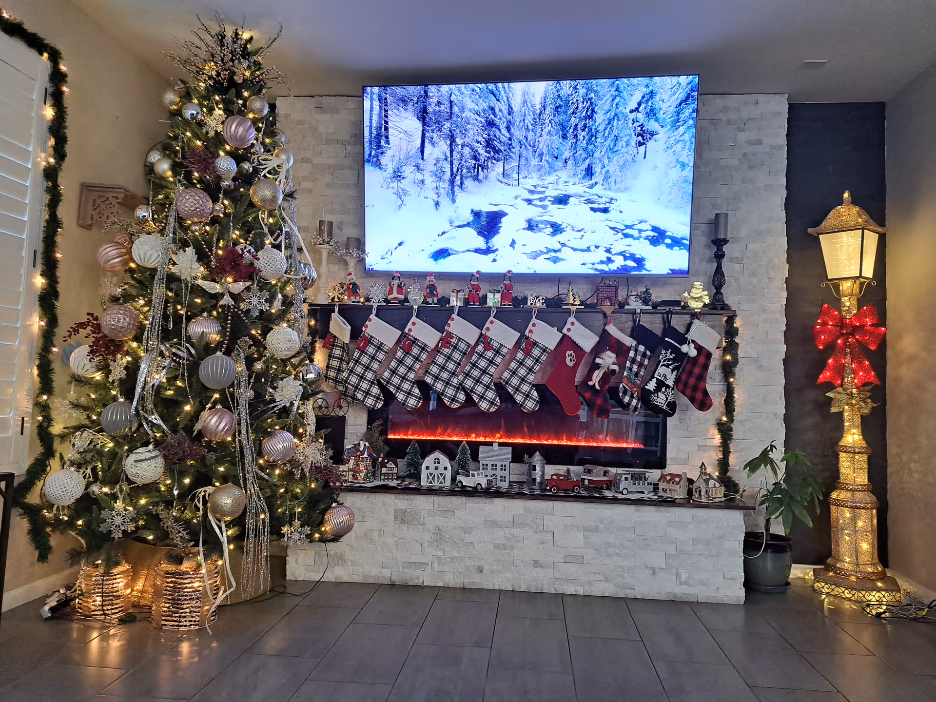 Festive living room scene with Christmas tree, stockings, garland, and lit fireplace.