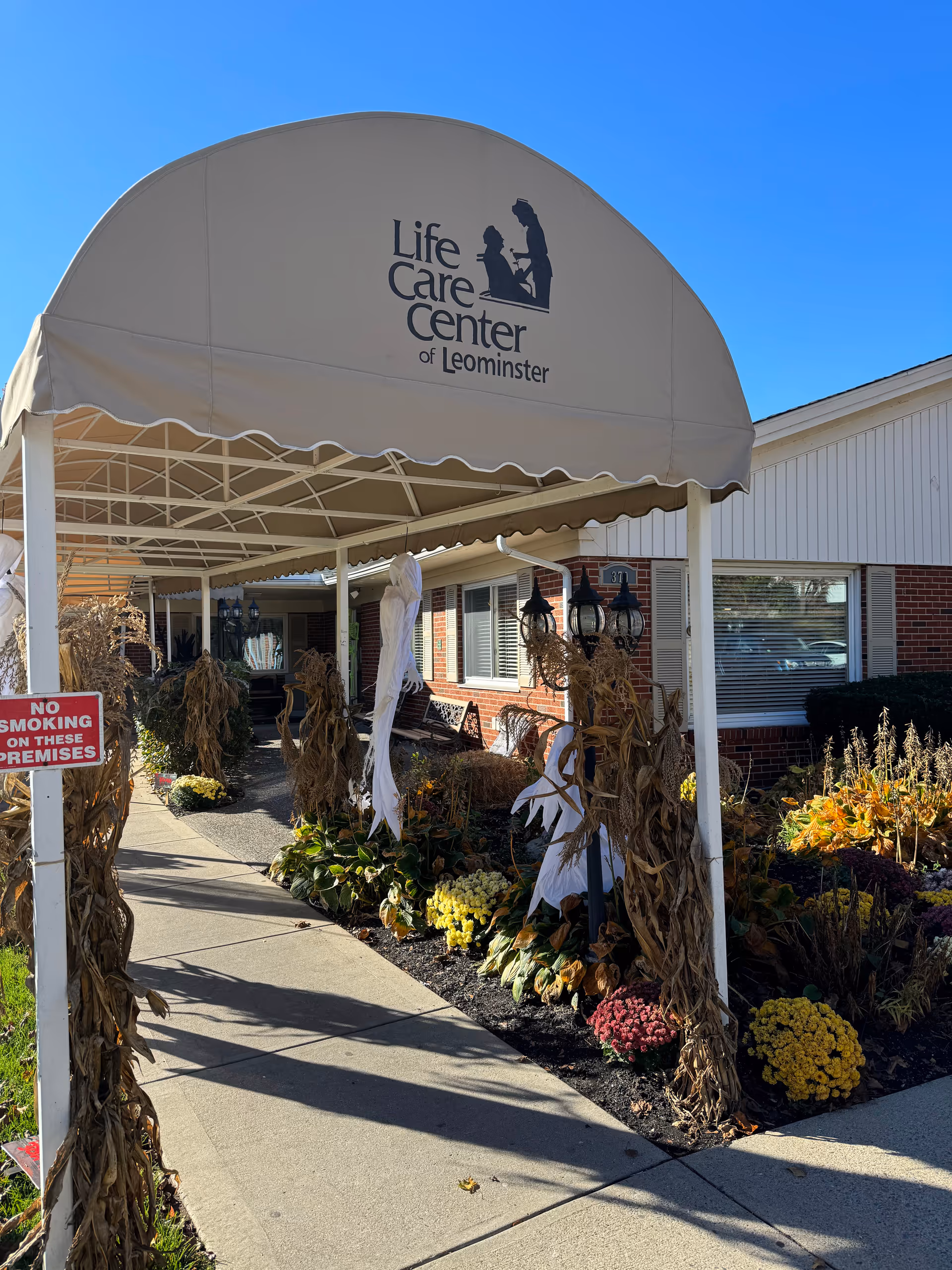 Entrance canopy of Life Care Center of Leominster with autumn flowers and pumpkins.