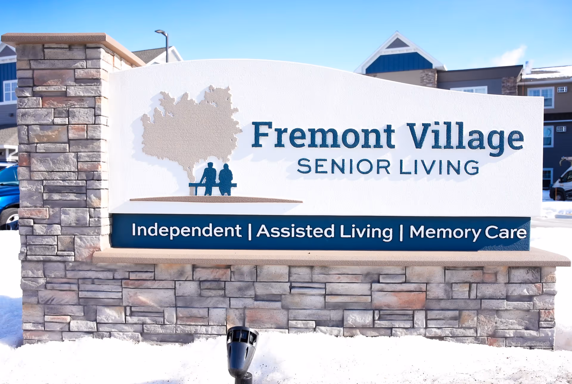 Outdoor stone sign reading Fremont Village Senior Living with care services listed.