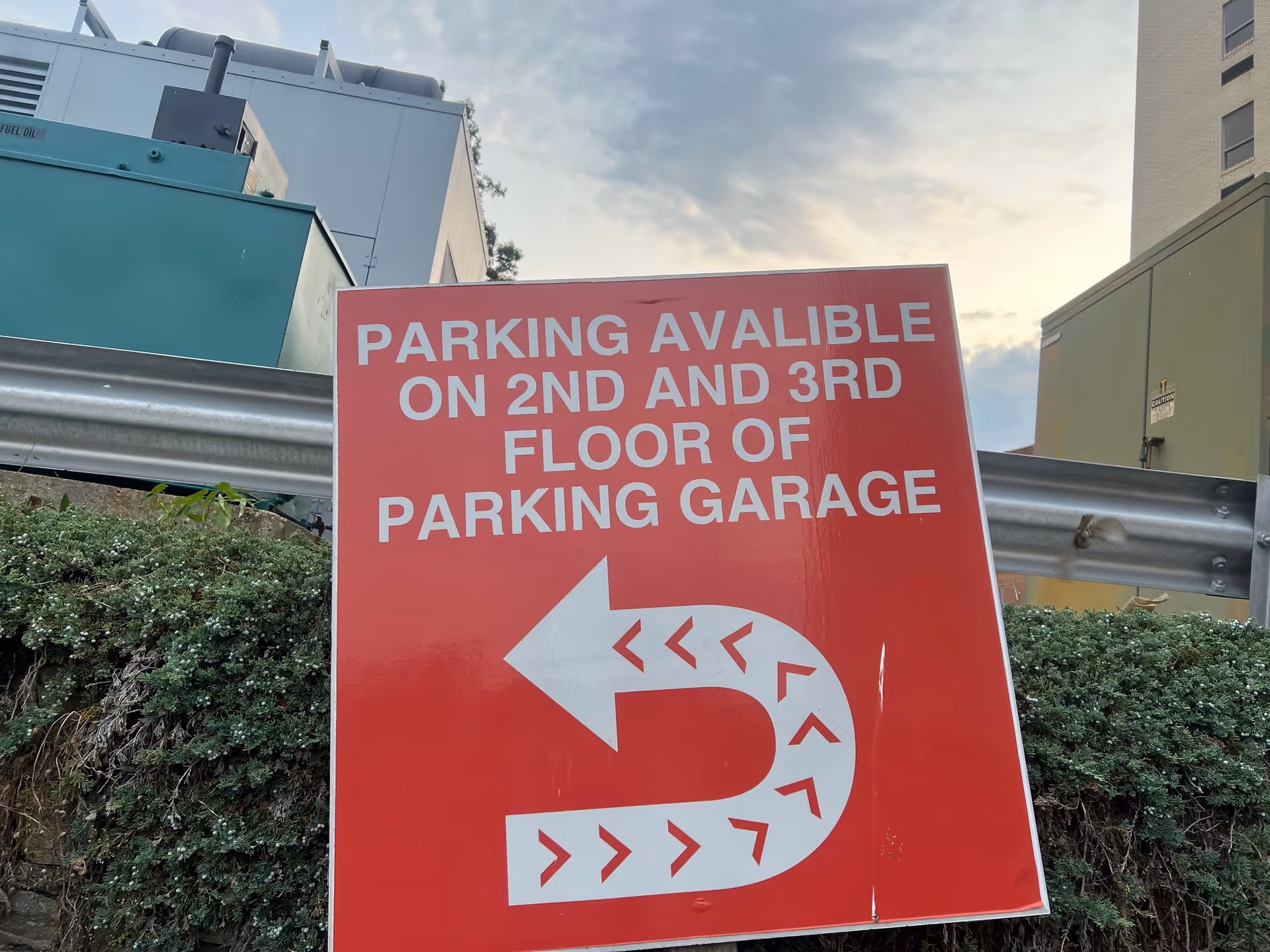 Large red outdoor parking sign with white text directing to garage on 2nd and 3rd floors.