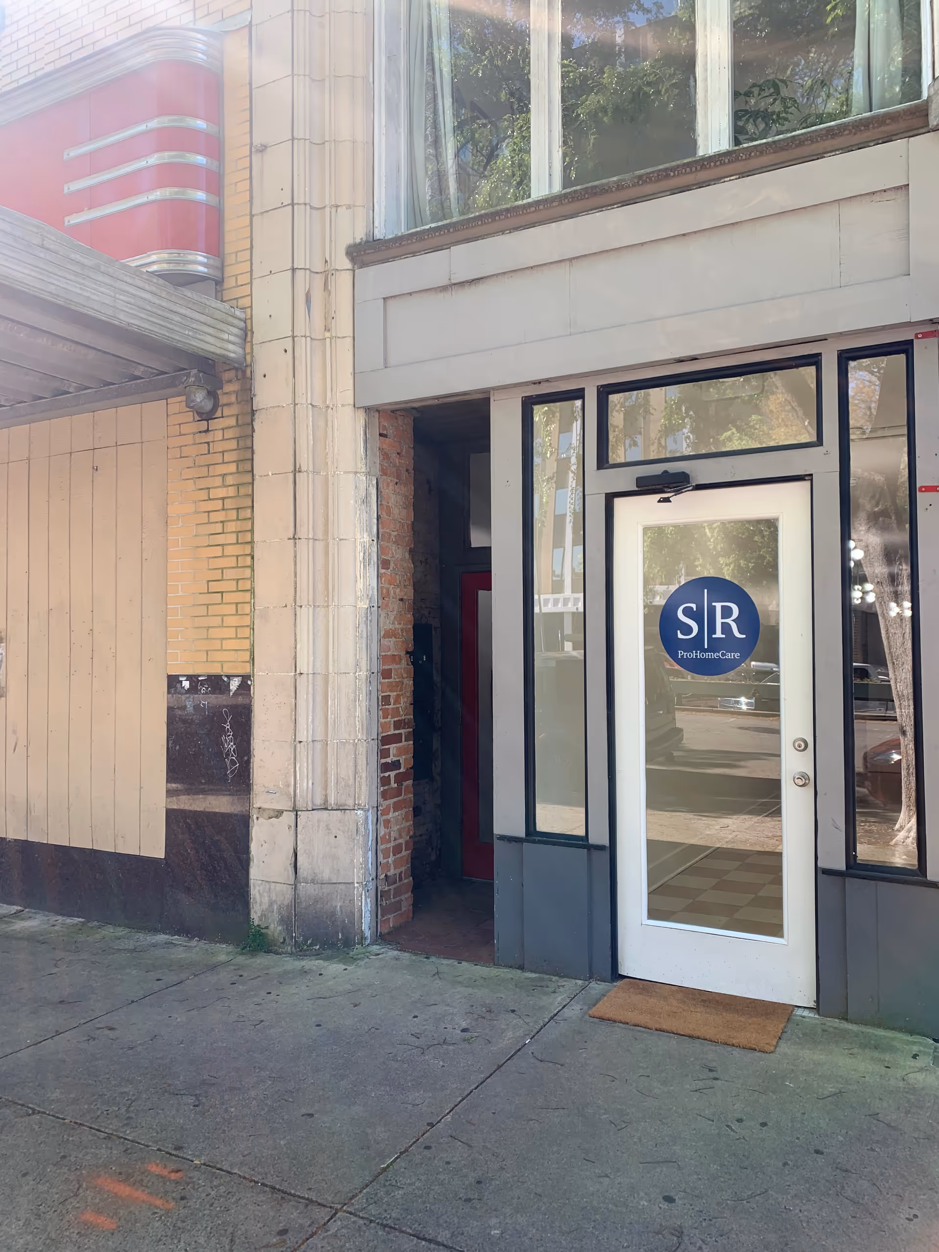 Exterior view of a building entrance with a glass door and SR ProHomeCare logo.