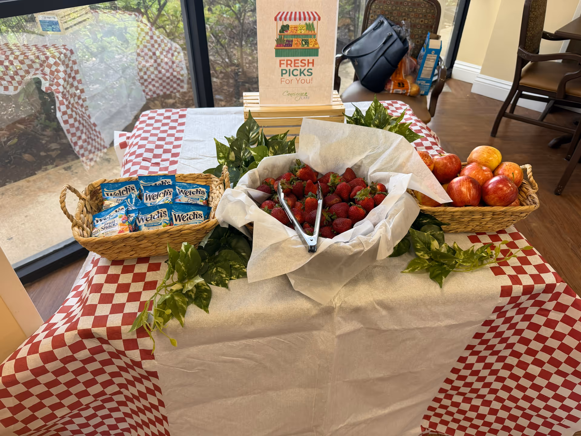 Table displays fresh fruit and snacks in a dining area with a checkered cloth.