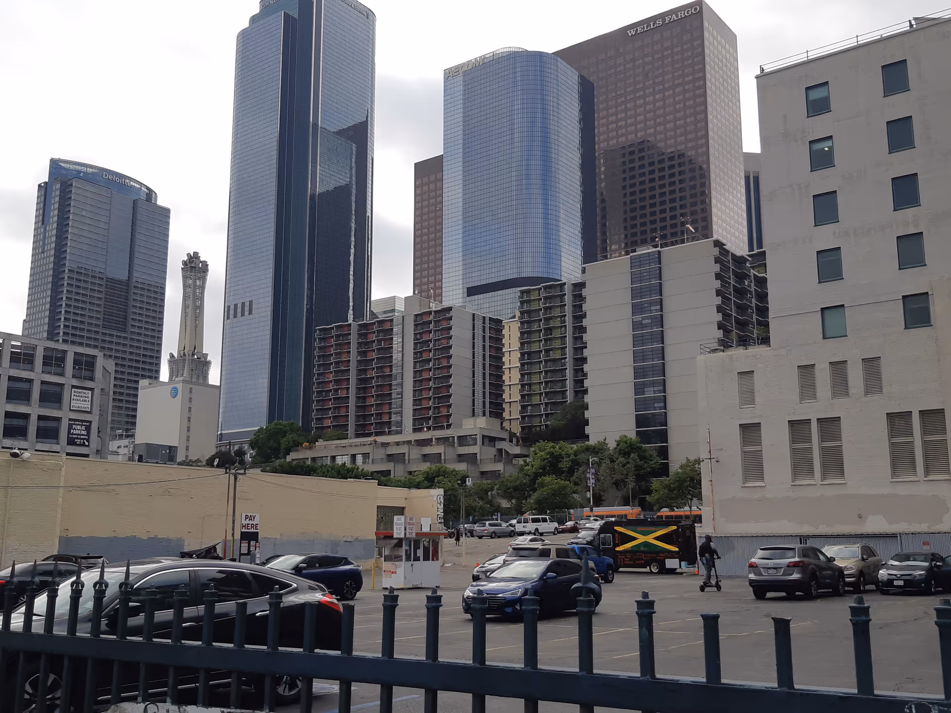 Urban cityscape with tall glass skyscrapers and a parking lot in the foreground.