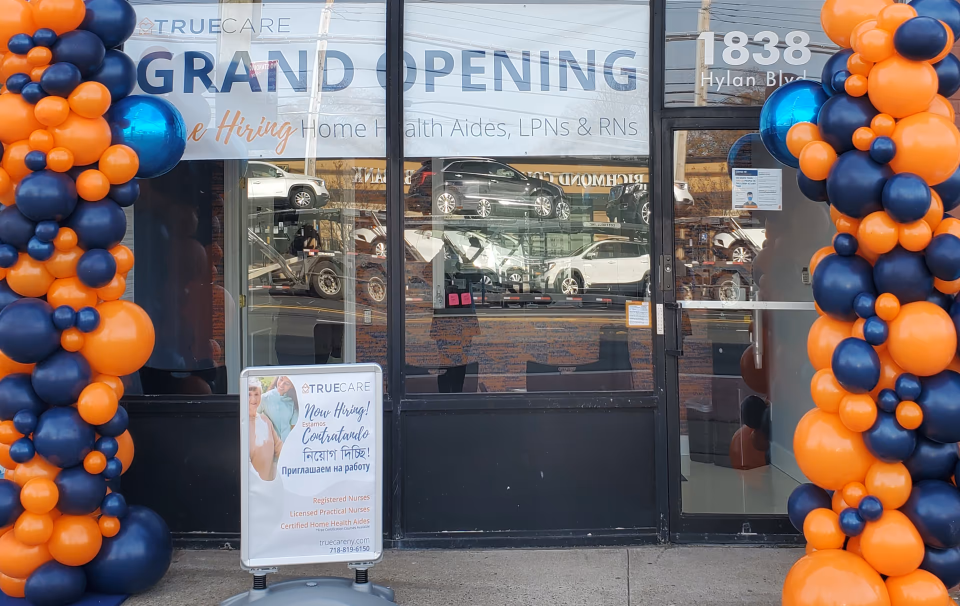 Storefront with grand-opening banner and orange-blue balloon columns outside the True Care storefront.