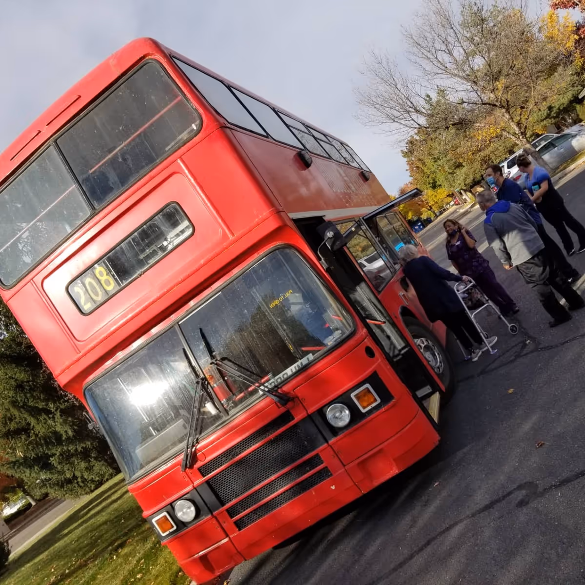 A red double-decker bus parked outdoors with several people nearby.