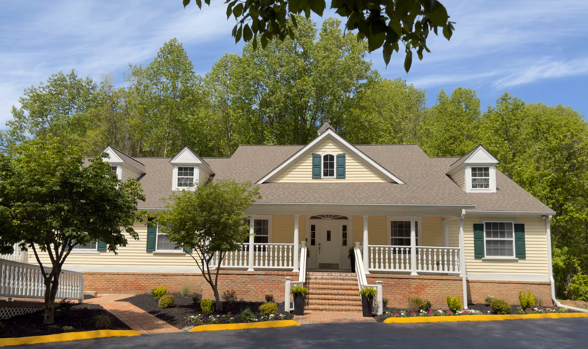 Wide view of Arcadia of Crofton I facility exterior with a front porch and green shutters.