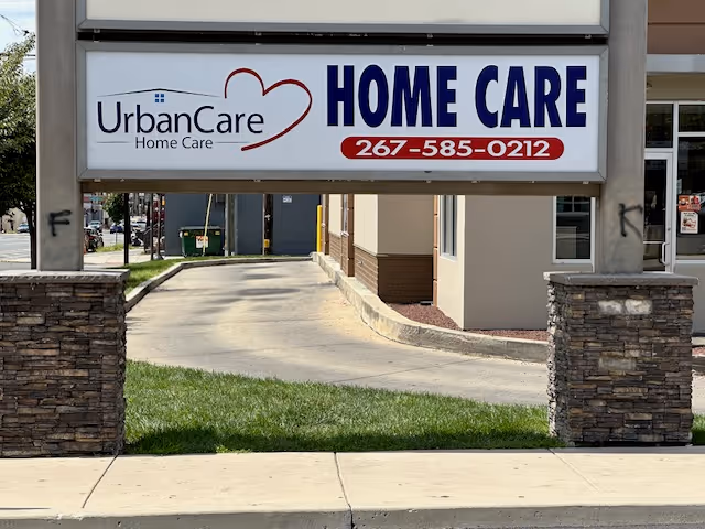 Exterior view of UrbanCare Home Care sign over entrance with stone pillars and walkway.