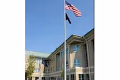 Front facade of Gino J Merli Veterans Center with flags flying above.