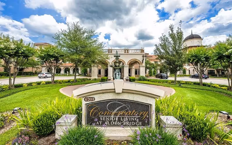 Front view of Conservatory Senior Living at Alden Bridge with sign, fountain, and greenery.