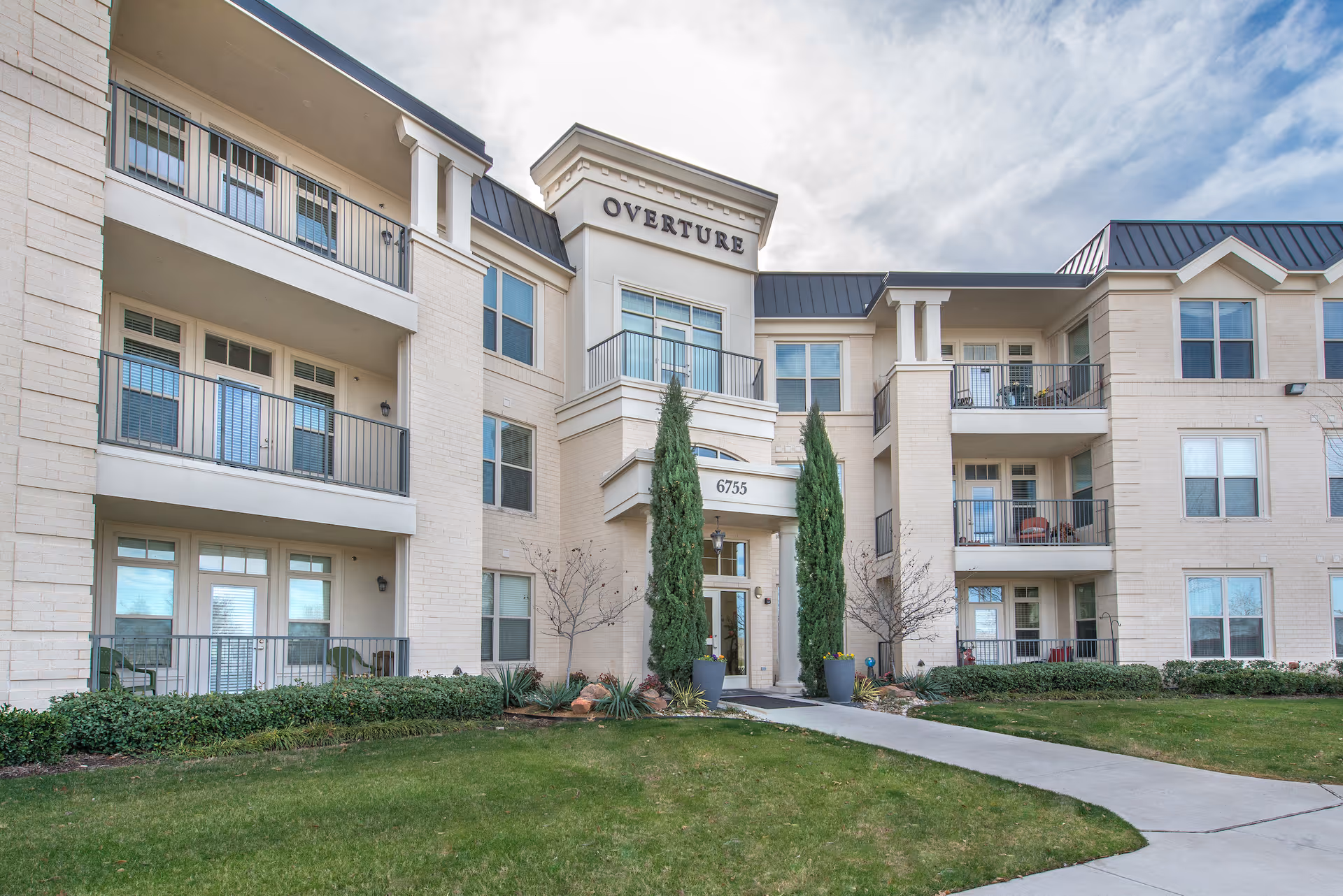 Exterior view of Overture Ridgmar senior living building with balconies and a central entrance.
