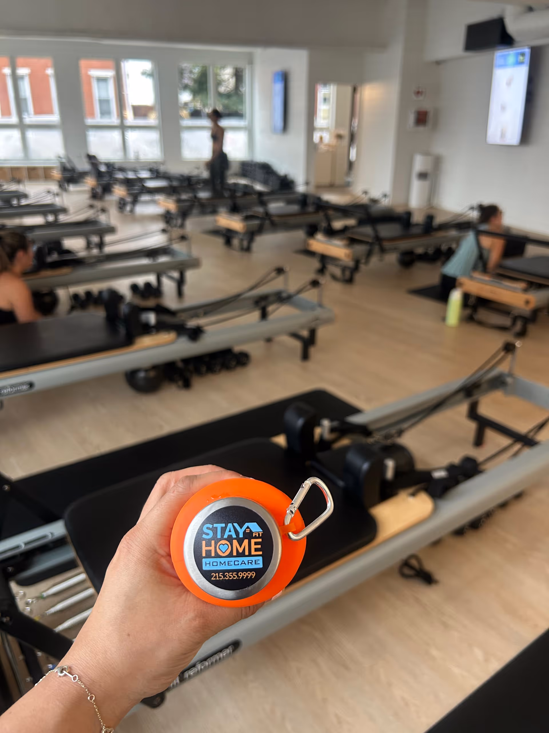 Person holds Stay at Home Homecare device in a pilates reformer gym.