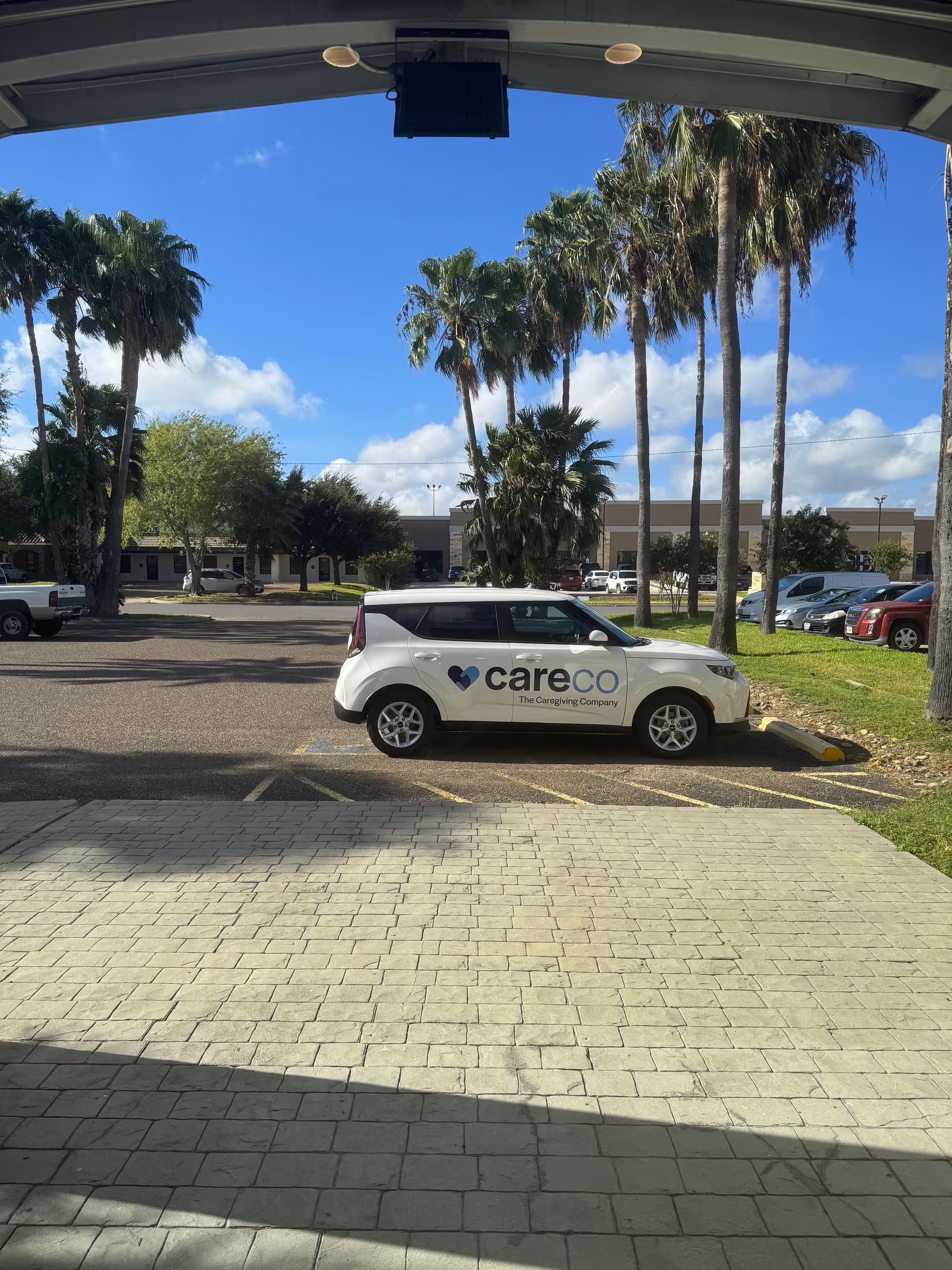 White CareCo car parked in a lot with palm trees.