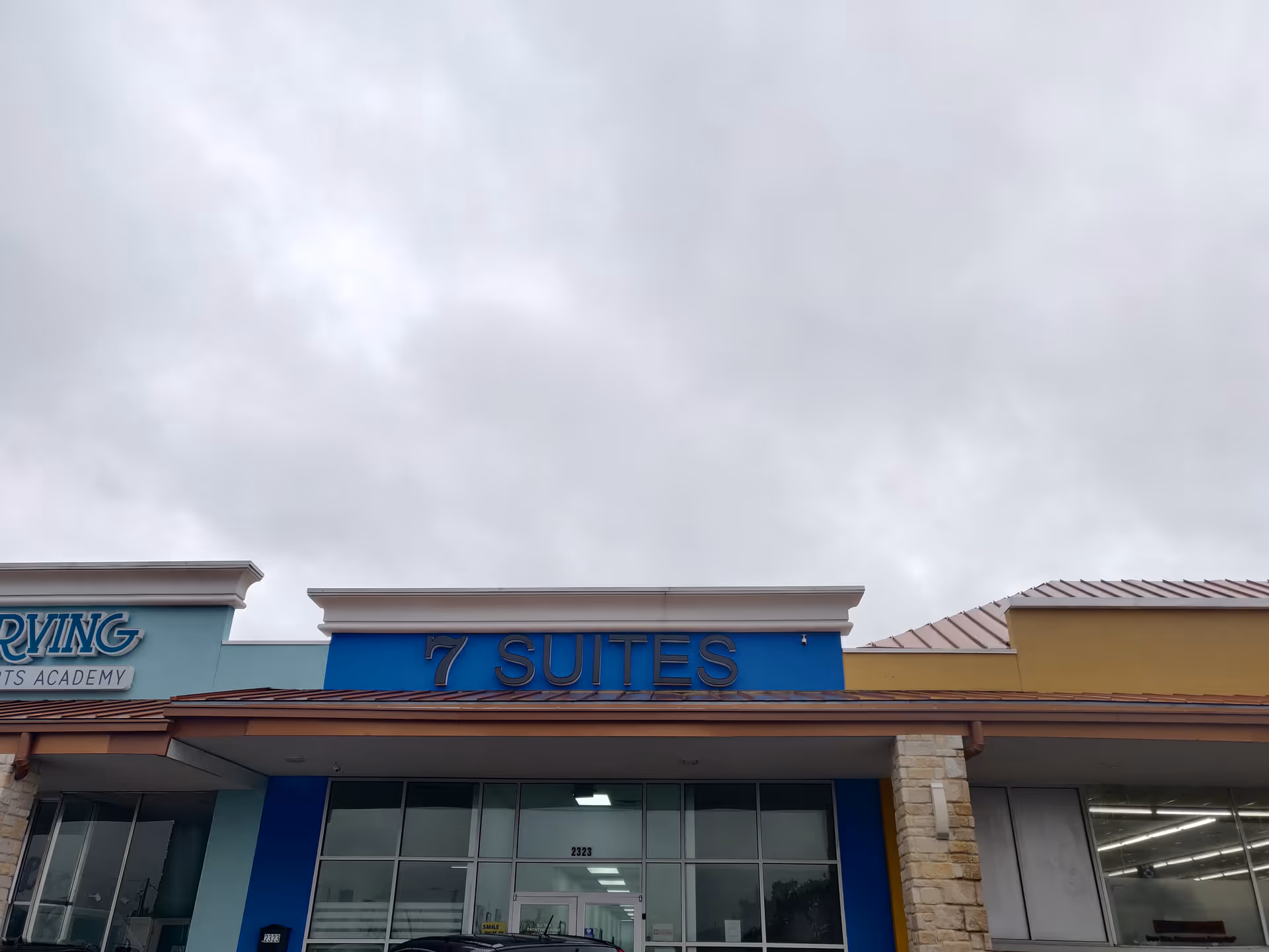 Front view of a building with blue 7 SUITES signage and glass storefronts.