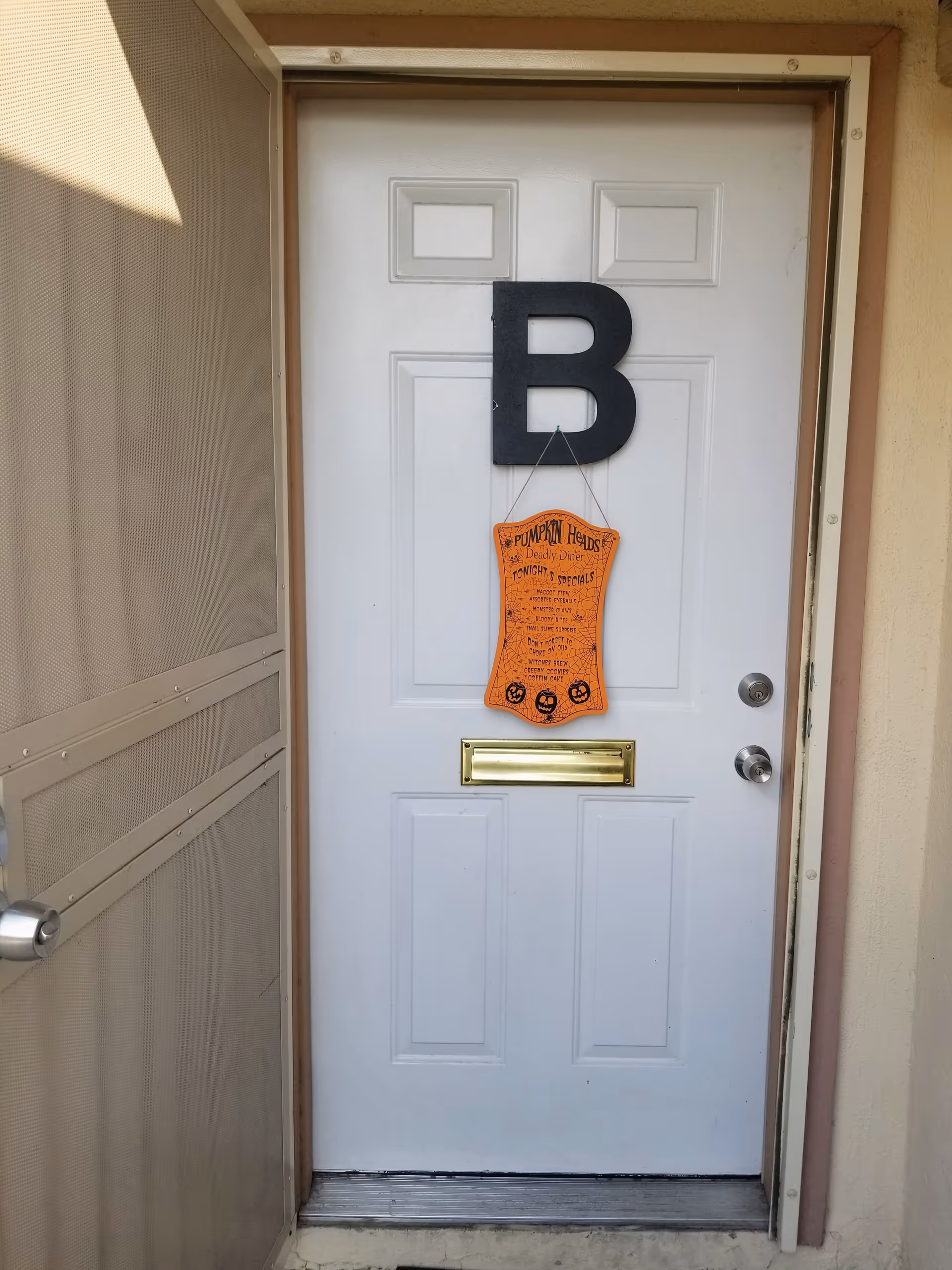 White exterior door with a large black B and orange Halloween banner.